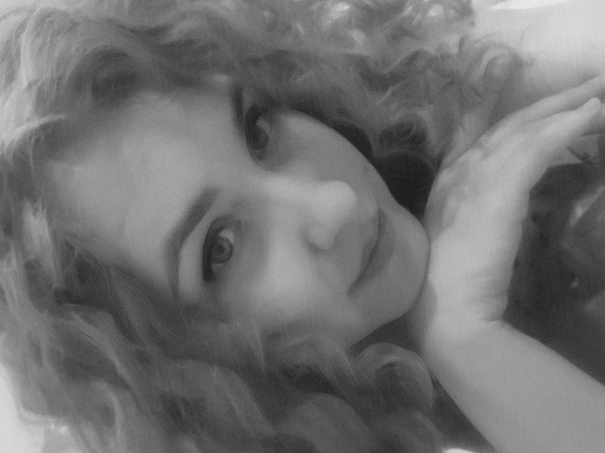 The image is a close-up, black and white portrait of a woman with curly hair. She is lying down, her head resting on her hand. Her gaze is directed at the camera. No information about Марковский, Russia can be determined from the image.