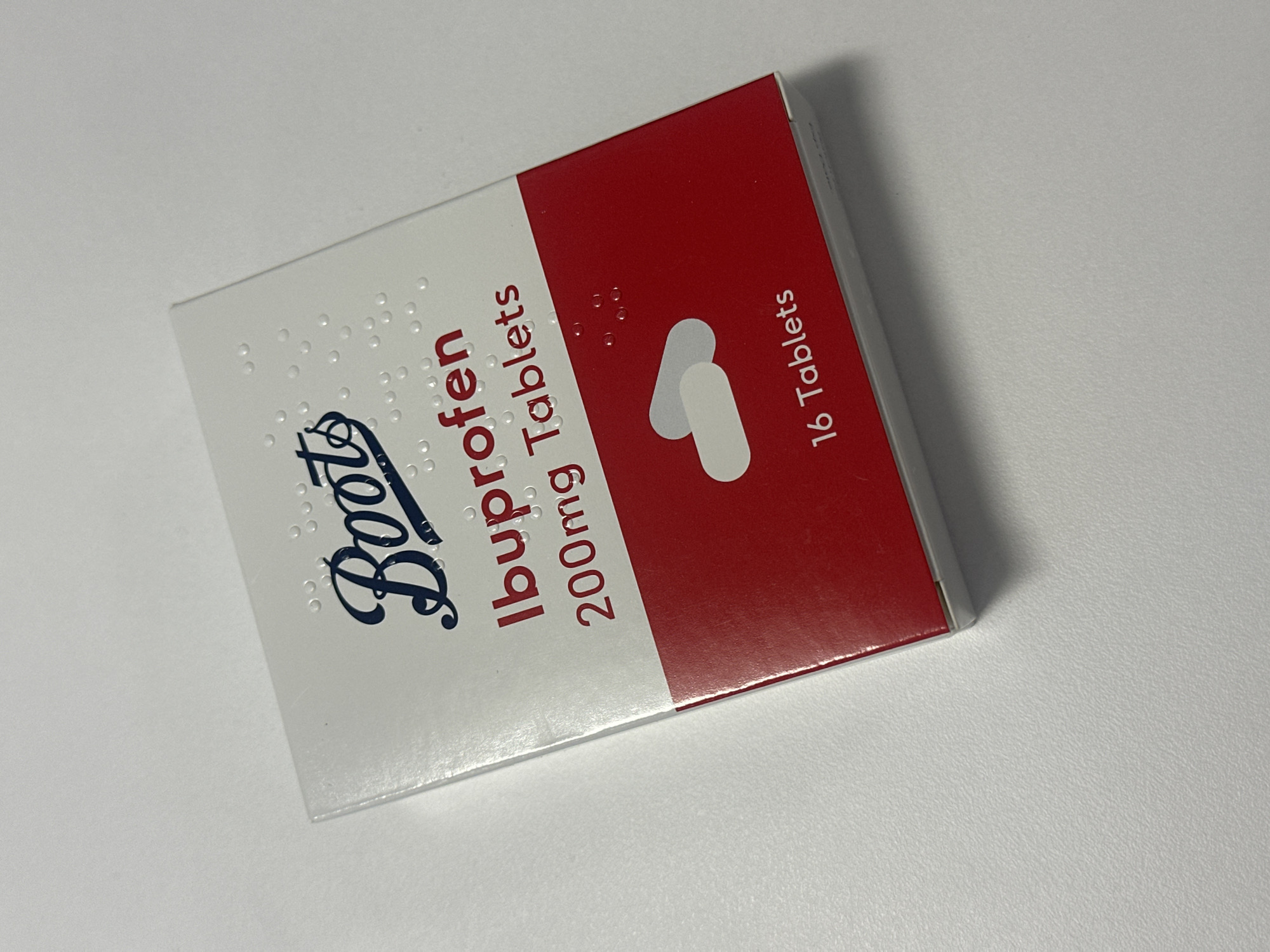 The image depicts a closed box of Boots Ibuprofen 200mg Tablets, containing 16 tablets. The box is white and red with the Boots logo and the text "Ibuprofen 200mg Tablets" printed on it. The location is the city of London, United Kingdom.