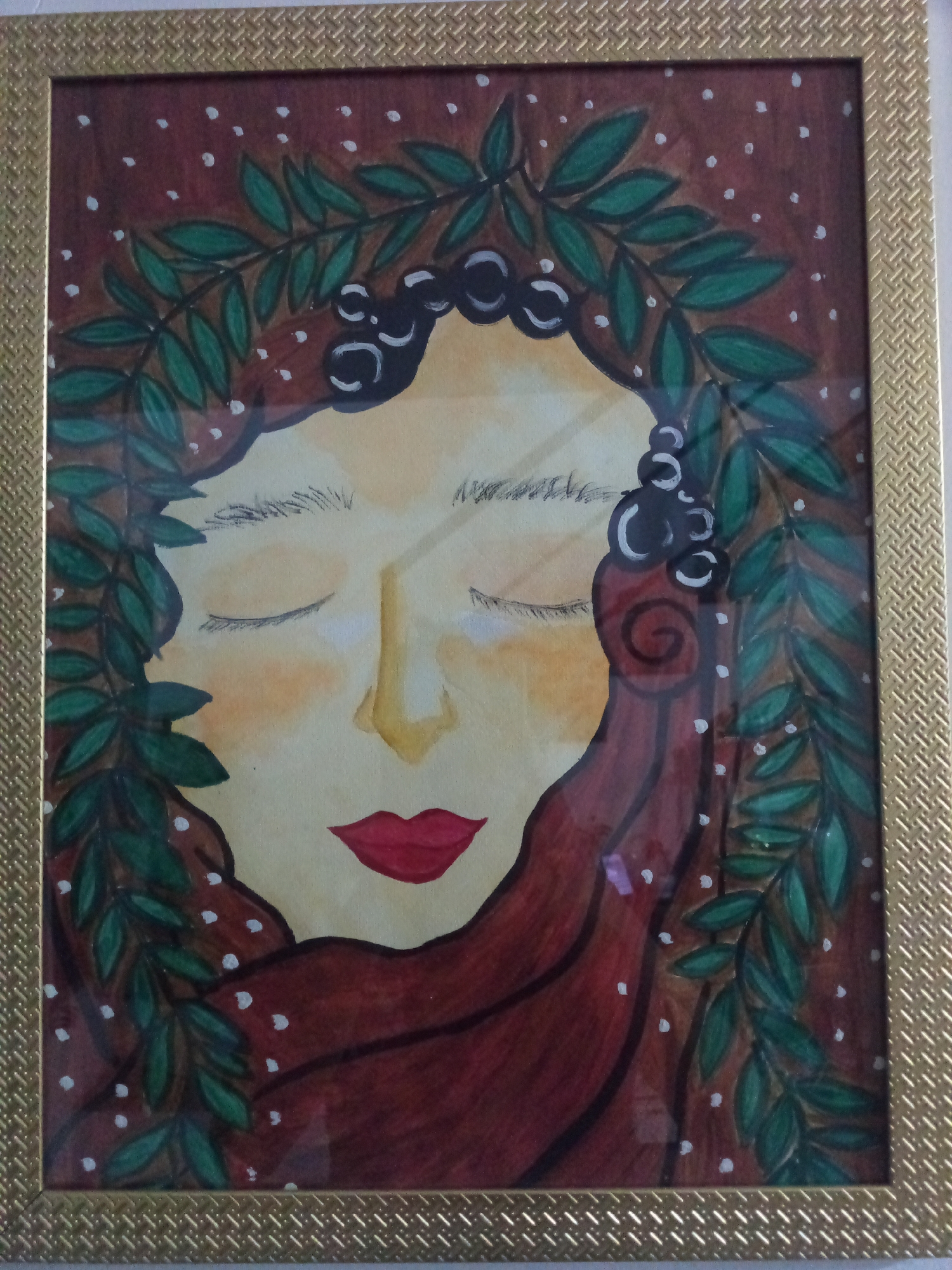 A framed artwork is visible. The artwork features a woman with her eyes closed, surrounded by a green leaf wreath. The background is reddish-brown with white dots. The woman's face is pale yellow, with red lips and dark hair. The frame is gold with a textured pattern. There is no information available in the image to determine the location in Davao City, Philippines.