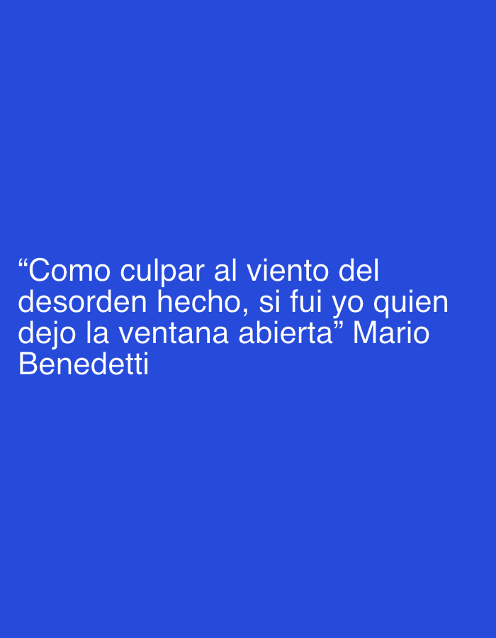 A digital image presents white, sans-serif text against a solid, uniform royal blue background. The text displays a Spanish quote: "Como culpar al viento del desorden hecho, si fui yo quien dejo la ventana abierta", followed by the author's name, "Mario Benedetti". The quote is formatted across multiple lines and is positioned within the upper-middle section of the image frame. No other objects, subjects, or environmental elements are visually discernible within the image. This scene is located in the city of Macho Muerto, Venezuela.