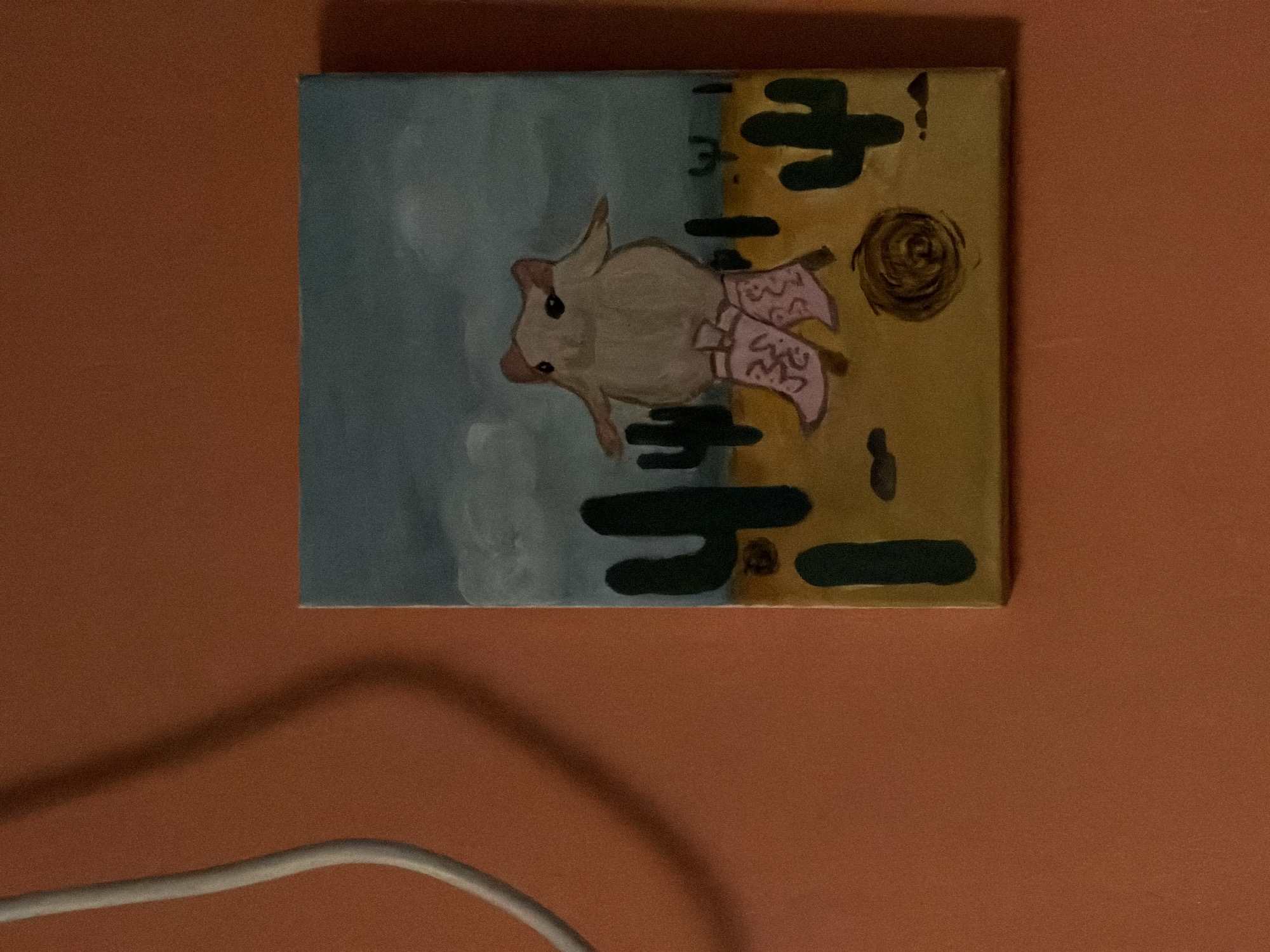 A painting hangs on an orange wall. The painting depicts a tan-colored animal wearing pink cowboy boots. The animal is against a background that is blue on one side and yellow on the other. Black symbols resembling cacti are painted on the yellow side. There is also a brown swirl on the yellow side. The painting is not in Tel-Aviv, Israel. A white cable is visible at the bottom of the frame.