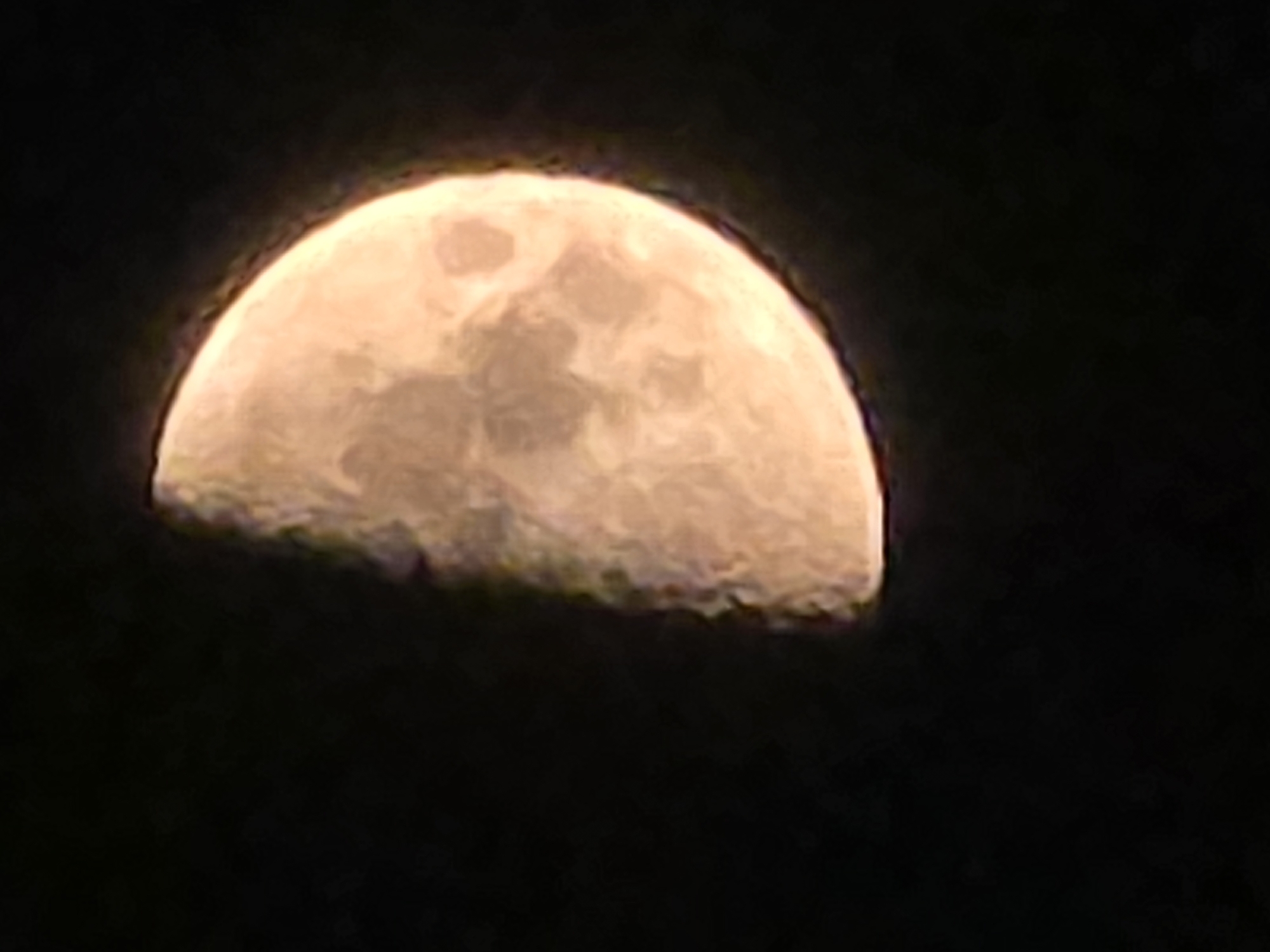 A half-moon is visible against a black sky. The moon is illuminated on the right side, with visible craters and texture on its surface. The left side of the moon is in shadow. The image is a close-up shot, with the moon filling a significant portion of the frame. There are no discernible landmarks or structures in the background, suggesting it is an outdoor, nighttime scene. The location in Yambol, Bulgaria, is not evident from the image itself.