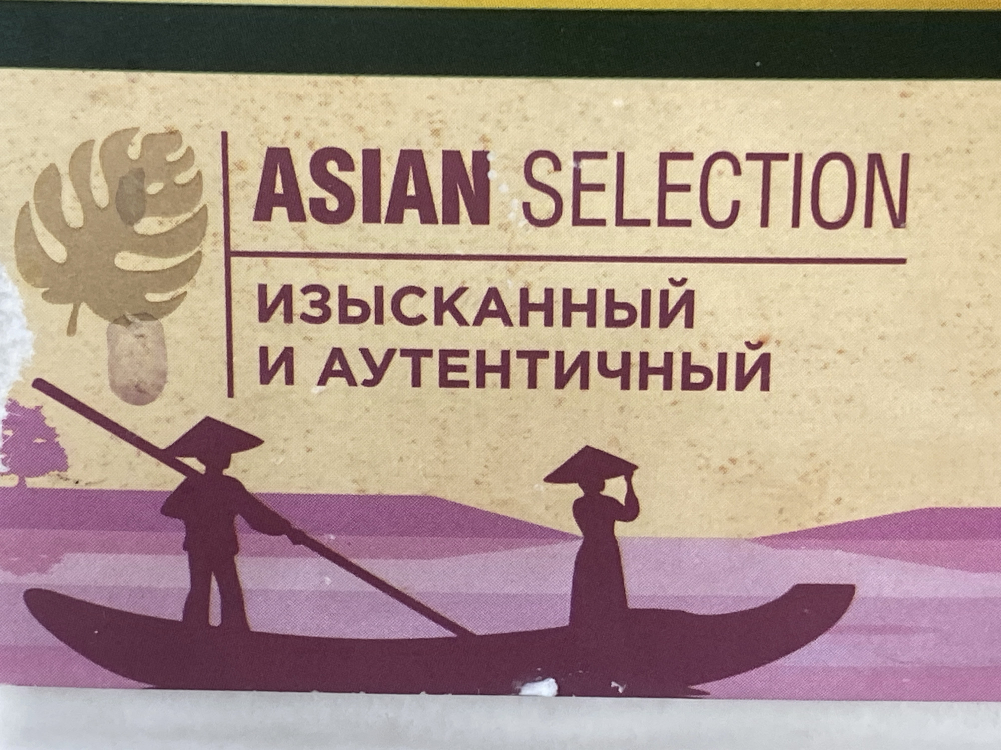 The image displays text and graphics on a light yellow background, with a dark green border at the top. The text in large, dark purple letters reads "ASIAN SELECTION". Below this, in smaller, dark purple Cyrillic script, it says "ИЗЫСКАННЫЙ" and "И АУТЕНТИЧНЫЙ", which translate to "Exquisite" and "Authentic". To the left of the text is a silhouette of a monstera leaf in a light brown color. The bottom portion of the image features a scene of two figures in conical hats, silhouetted in dark purple, poling boats through purple water. One figure is on the left, actively poling a boat, while the other is on the right, holding their hat. The scene evokes a traditional Asian waterway setting. The image does not contain any identifiable landmarks or context that would place it in the city of Panfilov, Kyrgyzstan.