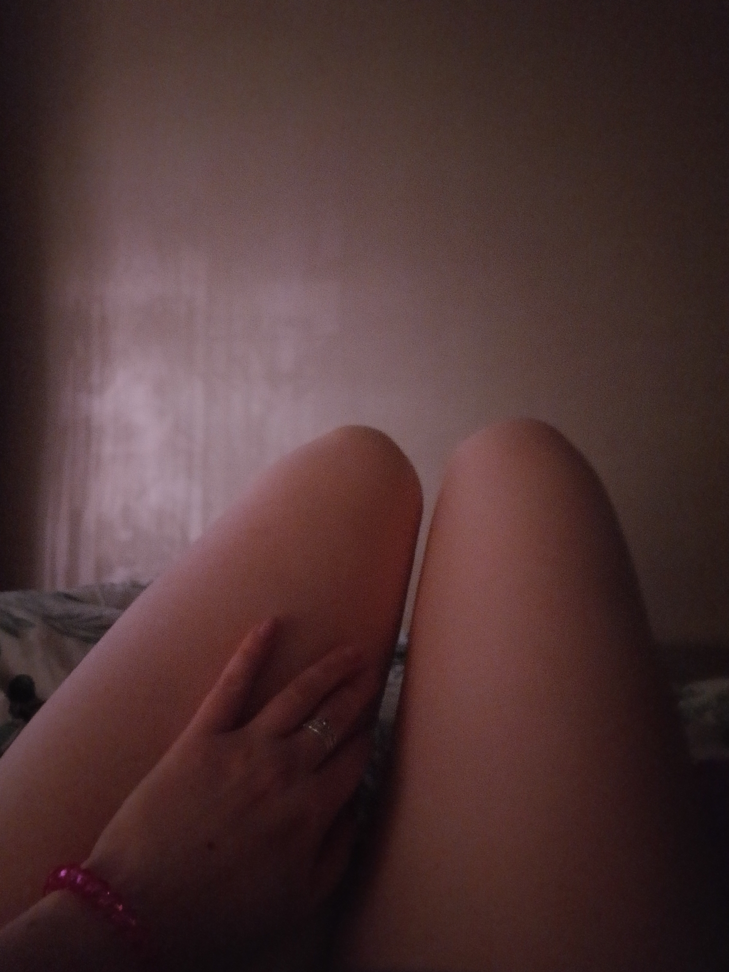 A close-up shot depicts a person's thighs and hand. The thighs are positioned in the center of the image, taking up a large portion of the frame. A hand rests on the left thigh, adorned with a ring and a pink beaded bracelet. The background is blurred and indistinct. There is no information in the image to suggest this was taken in Izhevsk, Russia.