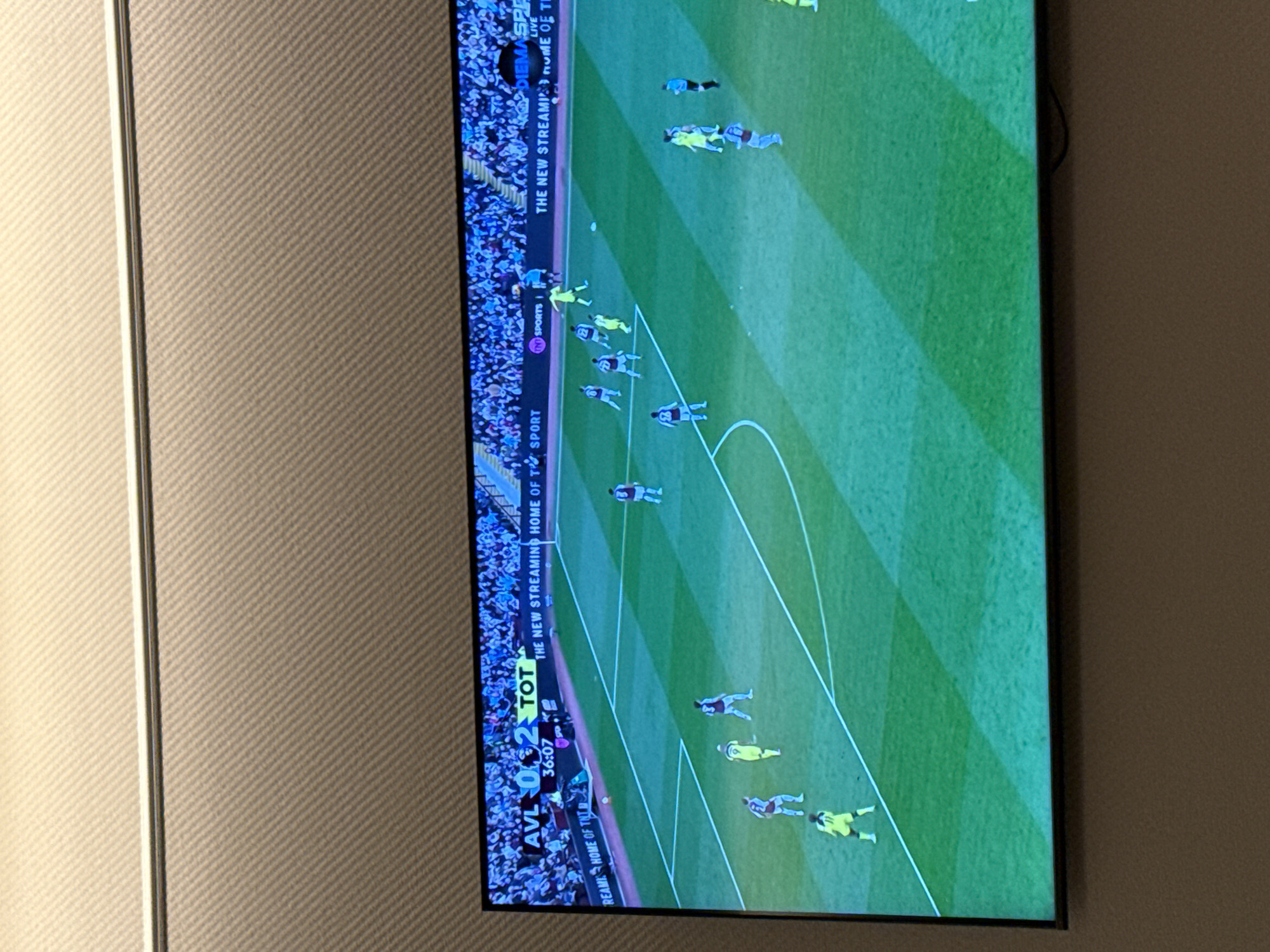 The image depicts a television screen displaying a live soccer game, showing the score as Aston Villa (AVL) 0, Tottenham Hotspur (TOT) 2, at 36:07 of the match. The image shows an overhead view of a soccer pitch with players in motion, and the broadcast branding indicates it is being streamed on TNT Sports, advertising itself as "THE NEW STREAMING HOME OF TOT." The location is not specified, and the city and state are unknown.