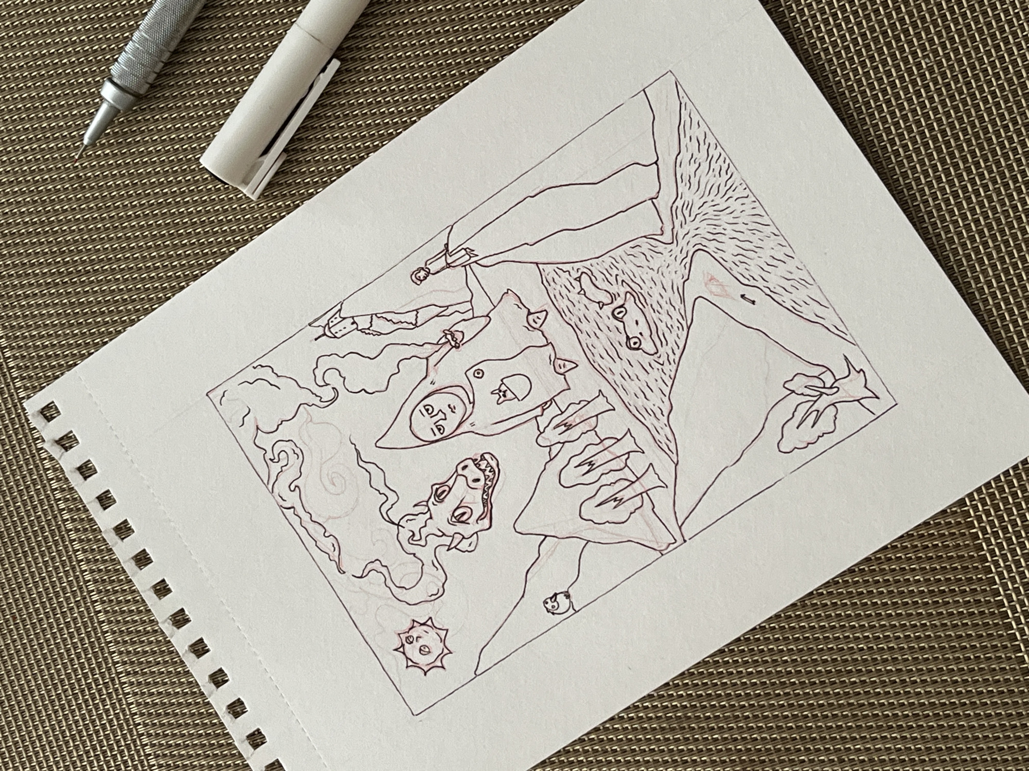 A drawing on a white, perforated notebook sheet depicts a fantastical landscape. The scene includes figures with exaggerated expressions, mythical creatures, and abstract shapes resembling clouds and a sun-like object. A silver mechanical pencil and a white pen with the cap off are situated on the upper-left corner of the paper. The sheet rests on a textured, brown surface.
