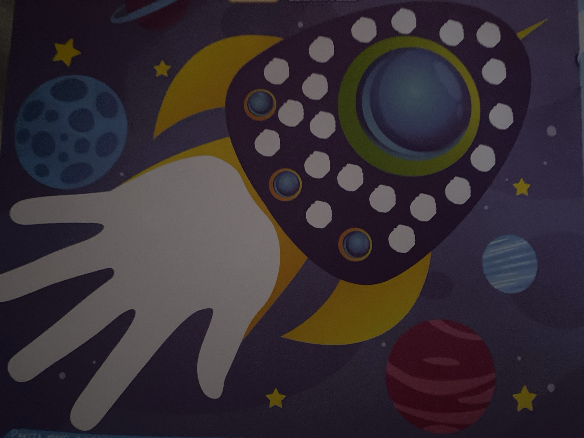 The image is a close-up, eye-level, medium shot of a colorful, stylized illustration depicting a space theme. The background is a dark purple, speckled with white dots representing stars and a few yellow stars. Dominating the upper left portion of the image is a large, pale white handprint, with the palm and fingers spread wide, appearing to be part of a larger rocket or celestial object. To the right of the handprint is a blue planet with dark blue craters. Below this is a yellow crescent moon shape.
In the lower half of the image, a large, dark purple, saucer-shaped object with a rounded, bumpy surface is visible. This object has several circular indentations, many filled with white dots, and two prominent circular blue windows with orange outlines. At the center of this saucer is a larger, dark blue circular area with lighter blue highlights, possibly representing a window or portal. A thin green ring encircles this central area. Extending from the bottom of the saucer is a sharp, yellow point, resembling the tail of a rocket or comet.
In the lower left quadrant, a round, reddish-pink planet with thin, darker red stripes is depicted. Below and to the right of this planet is a smaller, round, blue planet with thin, lighter blue stripes. Several small white dots are scattered throughout the scene. There is no indication of the city of Zgrade, Montenegro, or any real-world location. The image is a flat illustration with no depth or perspective cues.