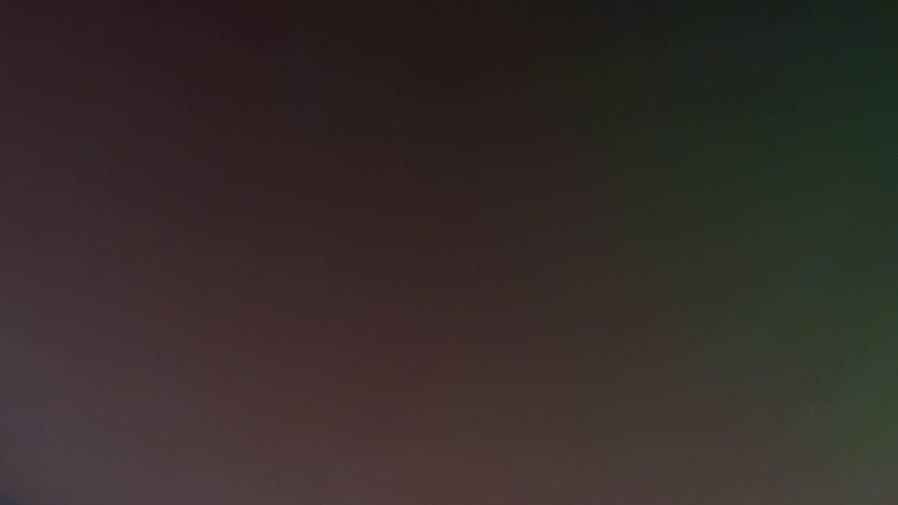 The image presents an abstract, dark, and smooth color gradient, with no discernible subjects, people, or objects. The primary colors transition from a deep, muted reddish-brown or dark maroon on the left and central parts of the frame, gradually blending into a dark, desaturated olive green or forest green towards the right side. A very subtle hint of dark blue or purple is present in the extreme bottom-left corner. A single, tiny, faint white speck can be observed in the lower-right quadrant.
The overall impression is one of low light, suggesting a dim environment, possibly nighttime. There are no activities or events taking place within the frame, nor are there any specific location cues visible. No text is present in the image. While the provided location context is Umarevtsi, Bulgaria, this information cannot be discerned from the visual content itself.
