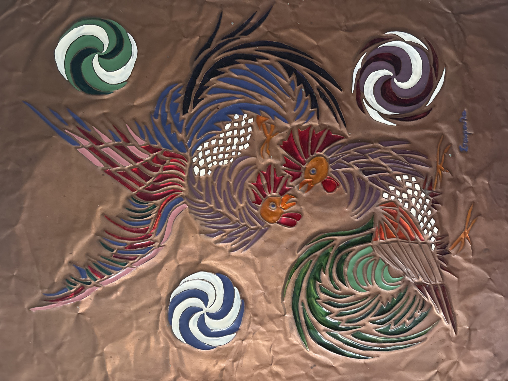 This is a close-up, overhead, forensic photograph of a copper relief art piece depicting two roosters and three circular decorative elements. The roosters are rendered in vibrant colors, with detailed feathers and combs. One rooster is positioned above and to the left of the other. The circular elements are abstract designs with swirling patterns of contrasting colors, such as blue and white, green and white, and purple and white. The background is a textured copper surface with visible wrinkles and dents, suggesting it is a wall-mounted or free-standing artwork. The signature "Σταυροπούλου" is visible in the lower right corner of the artwork. The image does not contain any elements that indicate its location in the city of Mandra, Greece.