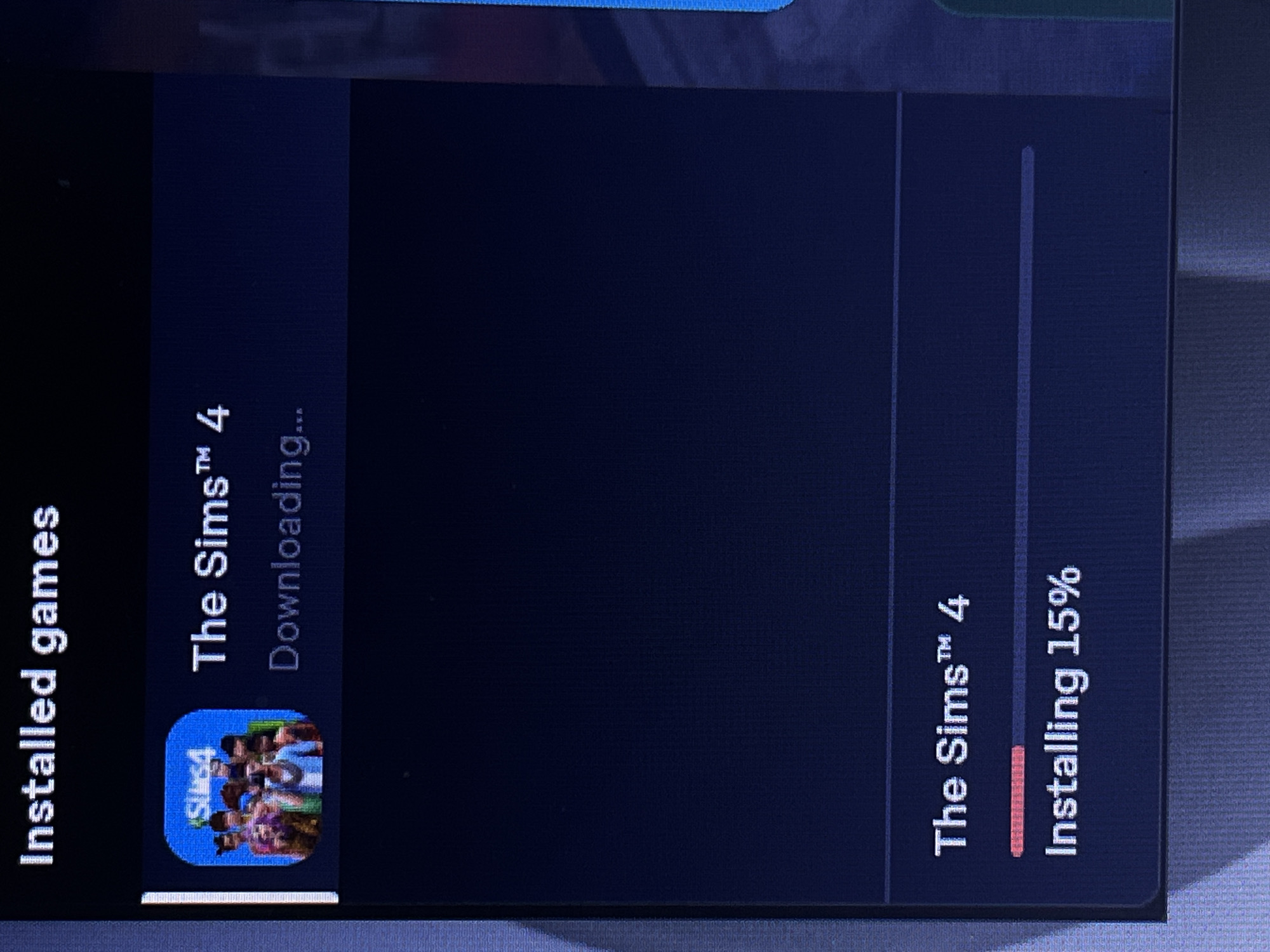The image displays a screenshot of a digital interface, likely from a game launcher or operating system. At the top, the text "Installed games" is visible. Below this, a section for "The Sims™ 4" is shown, with its icon to the left. The status indicates "Downloading...". Further down the screen, there is another entry for "The Sims™ 4" with a progress bar that is partially filled with red, indicating "Installing 15%". The overall background is dark blue. There is no information about the location in the city of Unknown, Unknown.