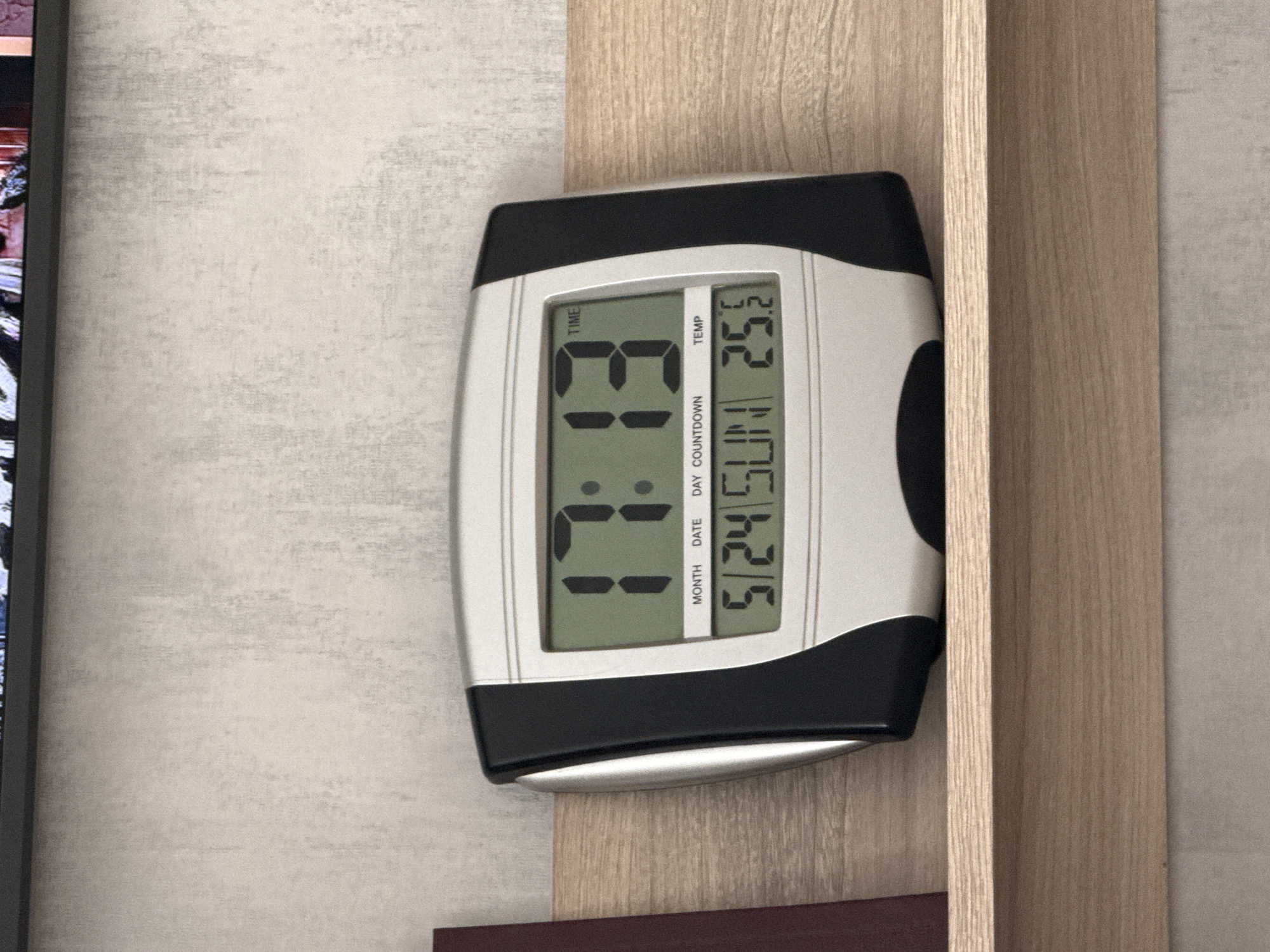 A close-up image shows a digital clock mounted on a wooden surface. The clock displays the time as 3:31, the date as May 24th, and the day as Sunday. The temperature is shown as 25.2 degrees. The clock has a silver and black casing. The wooden surface appears to be a shelf or part of a cabinet. The location is indeterminate and the claim about the city of Lovech, Bulgaria is not substantiated in the image.