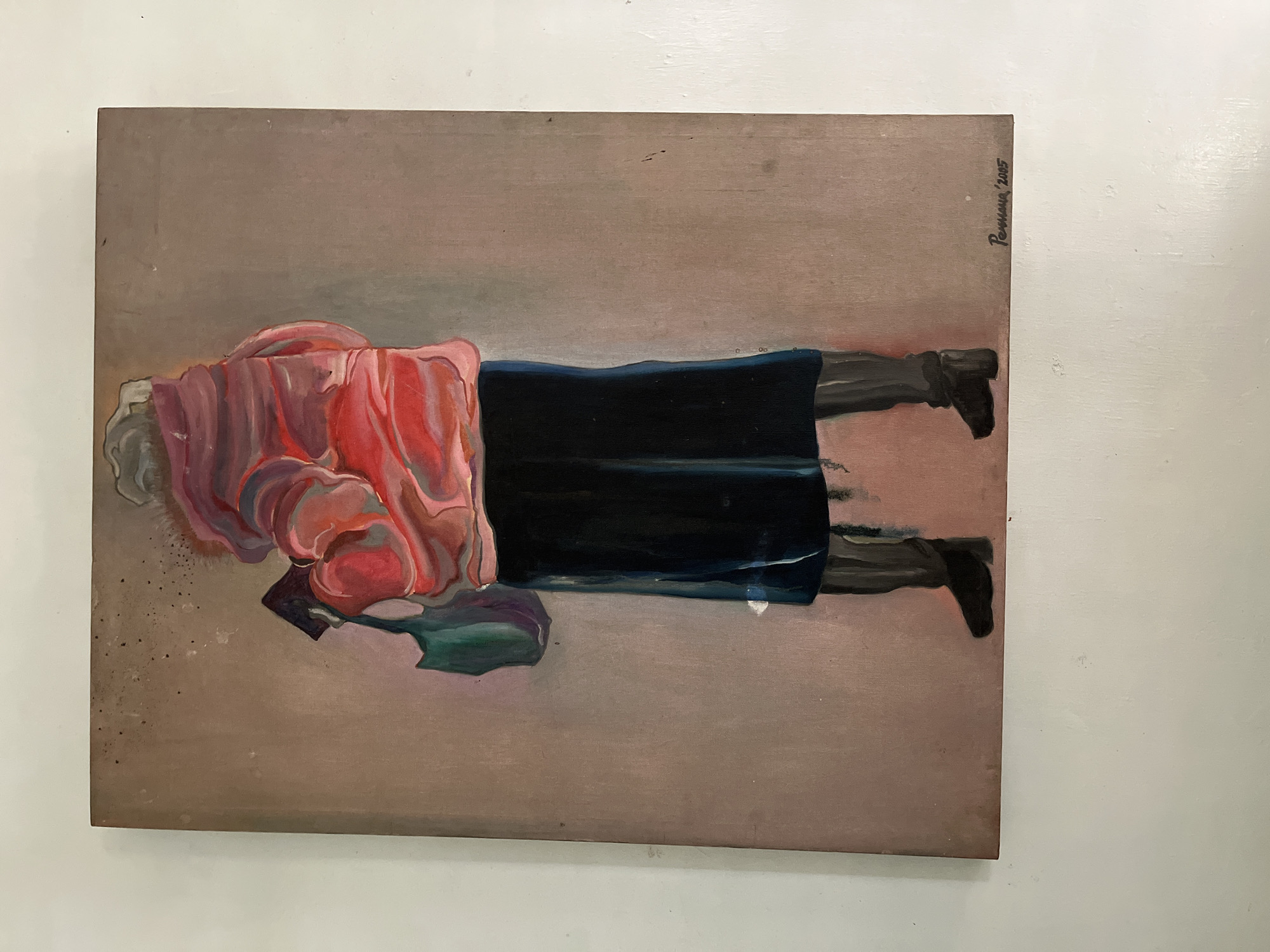 The image is a painting of a person viewed from behind, standing in front of a neutral, textured background. The person is wearing a bright pink, puffy jacket with a fur-lined collar, a dark skirt, and black boots. They are holding a green tote bag in their left arm and a dark object, possibly a book or wallet, in their right hand. The painting has a loose, impressionistic style with visible brushstrokes. In the bottom right corner, there is a signature that reads "Permana '2005". The painting is displayed on a white wall. The location of Karangkebagusan, Indonesia is not depicted in the image.