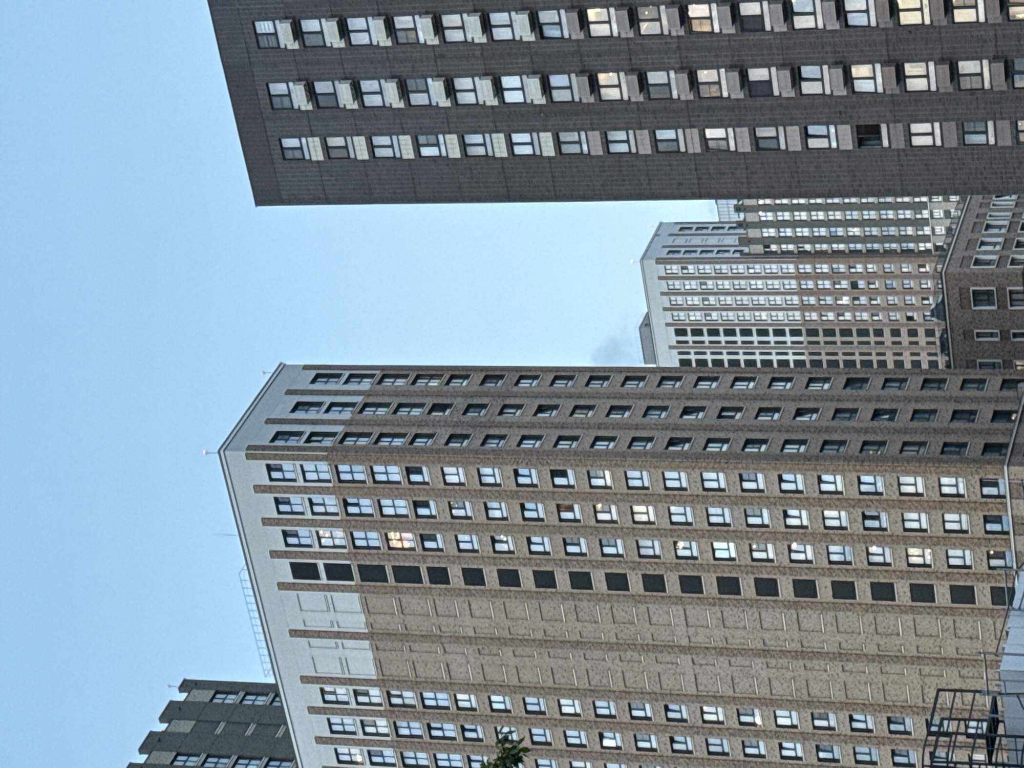 The image shows a low-angle view of several tall buildings with a grid of windows under a light blue sky. The buildings appear to be in a dense urban area. The architectural style is modern, with repetitive window patterns. The buildings are constructed of concrete. No people are visible. The specific location in Moscow, Russia, cannot be determined from the given image.