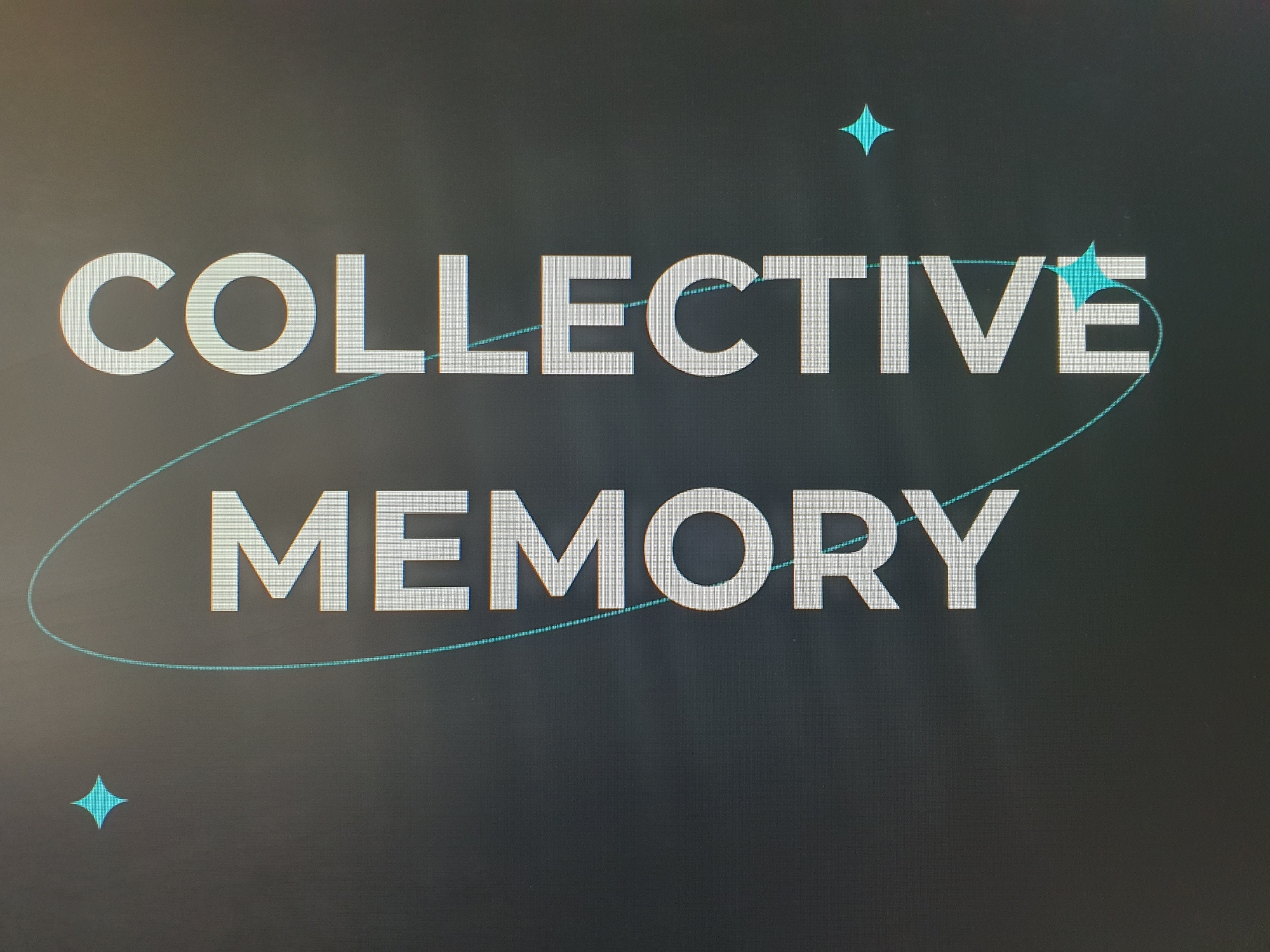 The image displays the words "COLLECTIVE MEMORY" in large, white, sans-serif font against a dark, textured background. The text appears to be on a screen or monitor. A thin, light blue elliptical line encircles the words "COLLECTIVE MEMORY" and extends above and below it. Two stylized light blue star-like shapes are visible, one near the top right of the "COLLECTIVE" text and another near the bottom left of the "MEMORY" text. The image does not depict any specific location in Tashkent, Uzbekistan, nor does it show any people, actions, or interactions.
