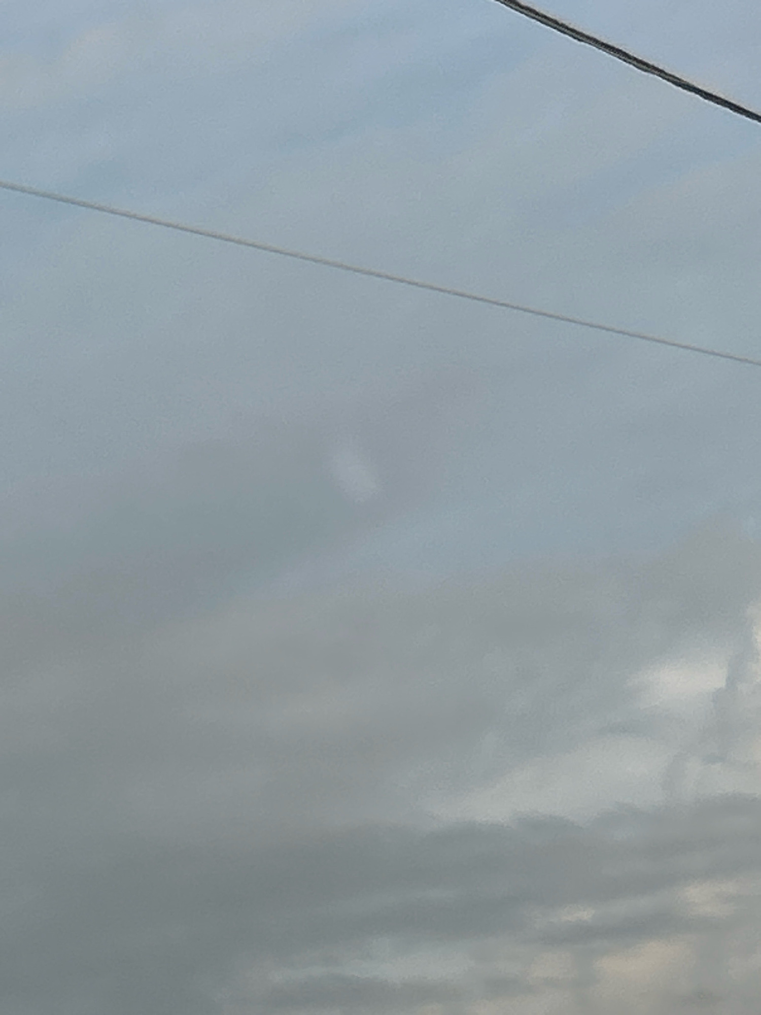 The image shows a cloudy sky with a faint, elongated white object in the upper-middle portion. Two wires are visible traversing the sky horizontally, one thinner and lighter in color, and the other thicker and darker. The overall impression is of an overcast day. The location is Robinson Township, USA.