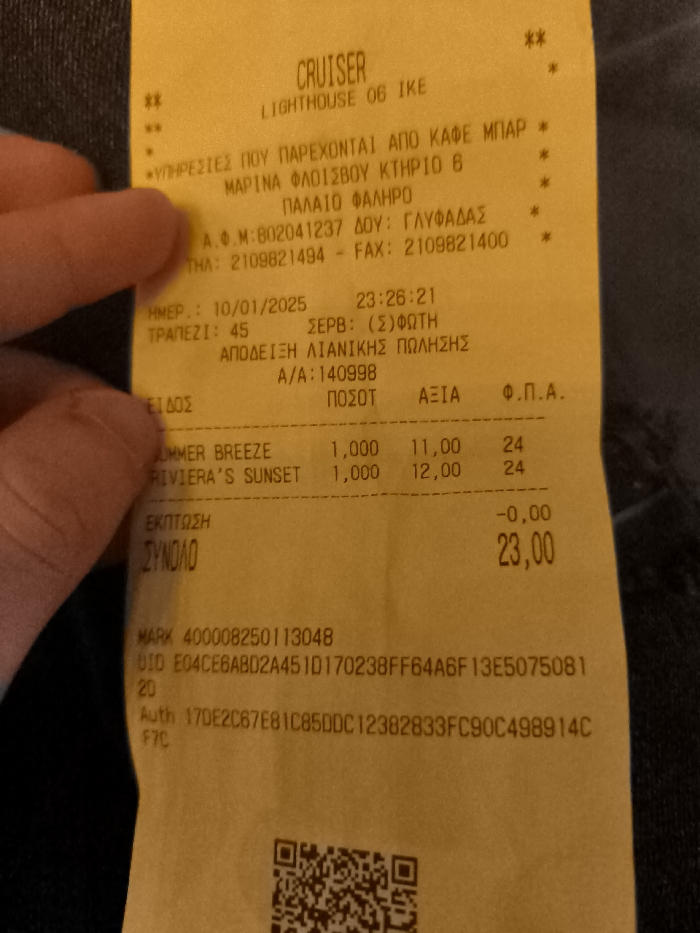 A person's fingers hold a yellow paper receipt from a business called "CRUISER LIGHTHOUSE 06 IKE." The receipt is presented against a dark, textured background, likely clothing.
The receipt documents a retail transaction that occurred on 10/01/2025 at 23:26:21. The location is "MARINA FLOISVOU KTHRIO 6, PALAIO FALIRO," which is in Palaio Faliro, Greece. The tax office (DOU) is listed as Glyfada, and the VAT ID (A.F.M.) is 802041237. Contact numbers are also provided (Tel: 2109821494, Fax: 2109821400). The server for table 45 is identified as Foti.
Two items are listed: "SUMMER BREEZE" for 11.00 and "RIVIERA'S SUNSET" for 12.00, each with a quantity of 1.000 and a VAT rate of 24%. There was no discount applied. The total amount due is 23.00.
Additional details on the receipt include a MARK number (400008250113048), a UID (E04CE6AB02A451D170238FF64A6F13E5075081), and an authorization code (Auth 17DE2C67E8IC85DDC12382833FC90C498914CF7C). A QR code is visible at the bottom of the receipt. The Greek text at the top, "ΥΠΗΡΕΣΙΕΣ ΠΟΥ ΠΑΡΕΧΟΝΤΑΙ ΑΠΟ ΚΑΦΕ ΜΠΑΡ," indicates "Services provided by a cafe bar."