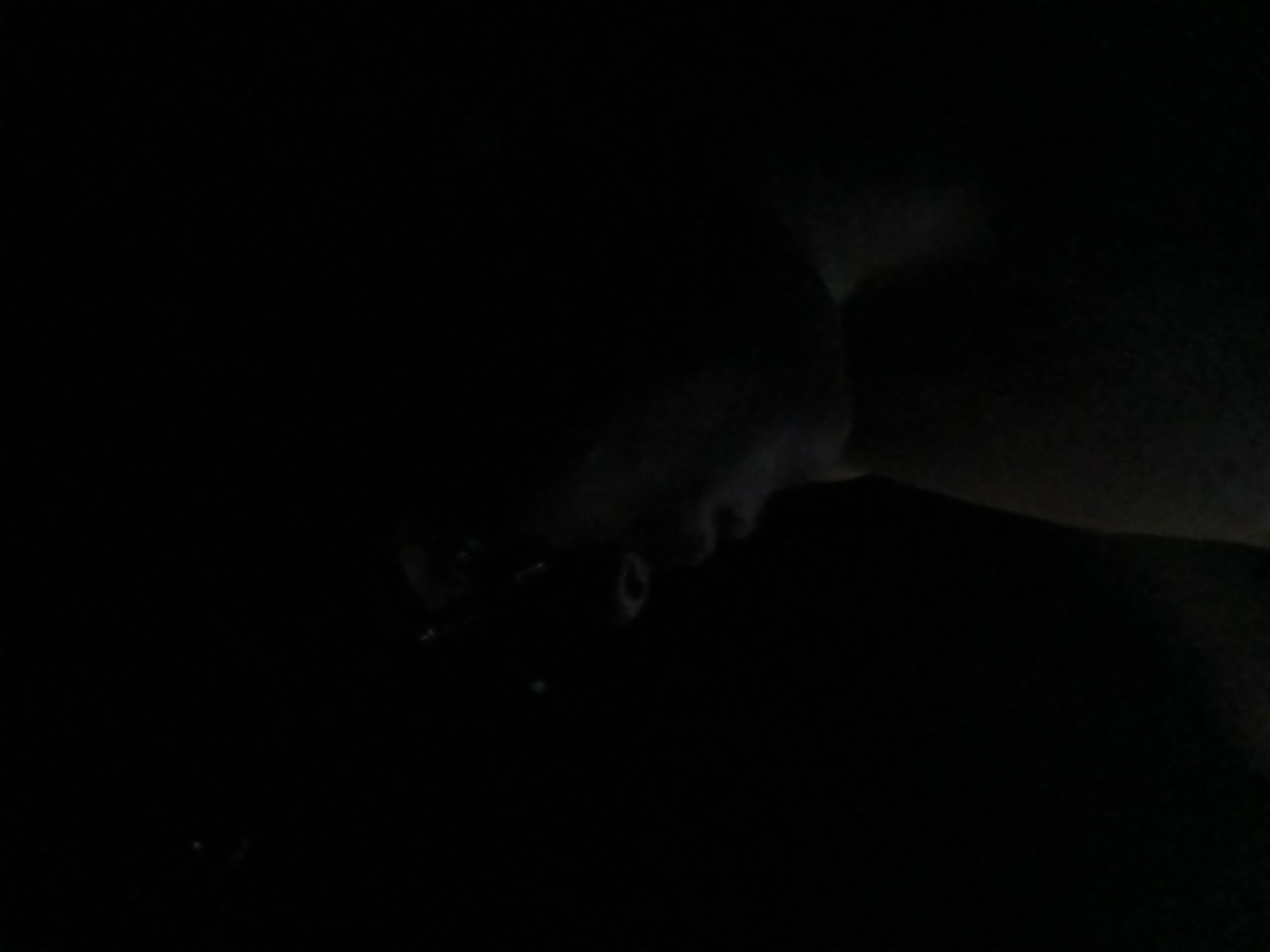 The image is very dark, making detailed observation difficult. A person's face is dimly visible in the lower center, appearing to be tilted downwards. The surrounding area is enveloped in darkness. No information about Altagracia, Venezuela or specific subjects, objects, actions, interactions, or environmental details can be determined from the provided image.