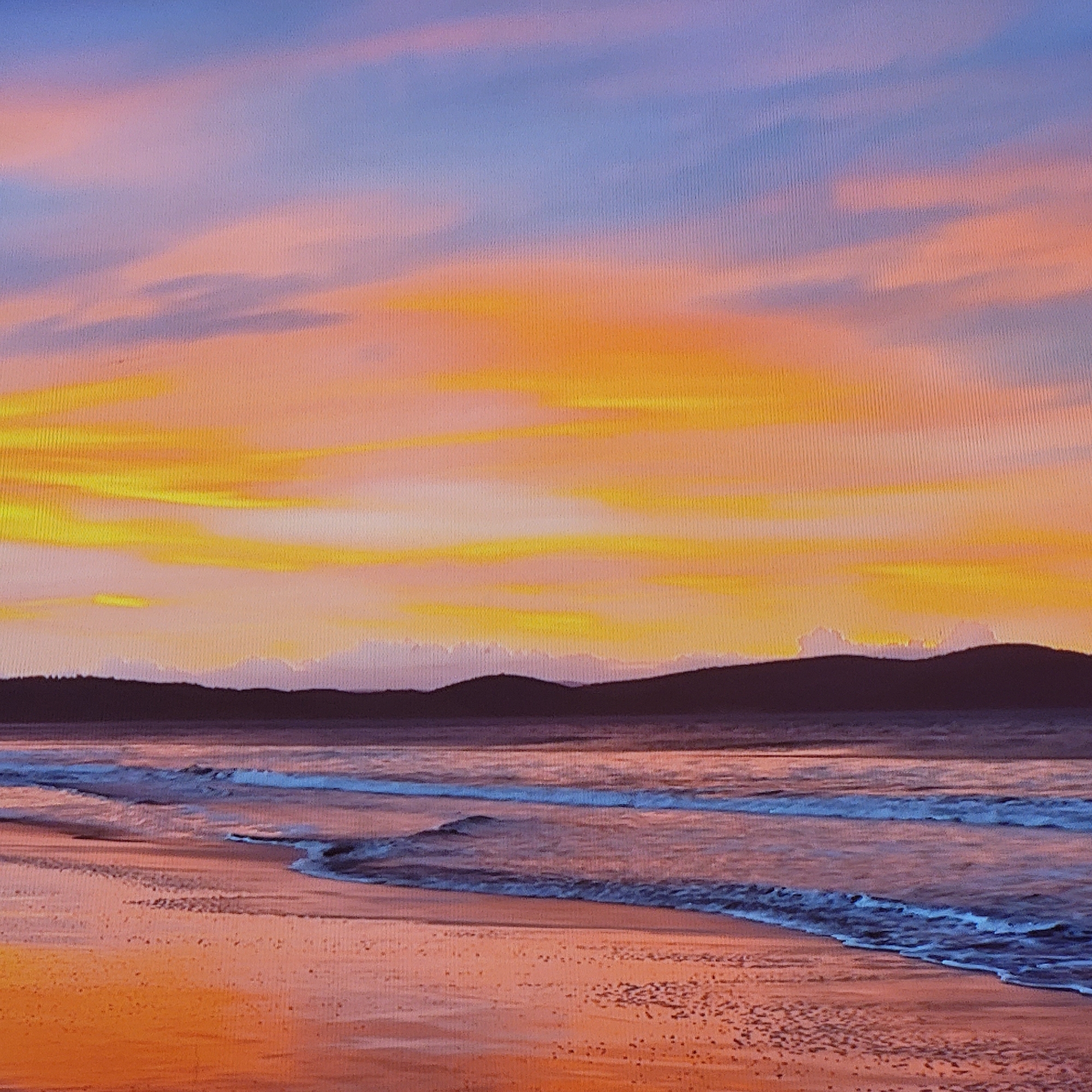 The image depicts a coastal landscape at sunset. The sky transitions from blue at the top to orange and yellow hues near the horizon. Clouds stretch across the sky, mirroring the warm colors. Below the sky, a dark, silhouetted landmass sits on the horizon, possibly a coastline or hills. The ocean extends to the shore with gentle waves washing onto the sandy beach. The beach and water reflect the colors of the sky, creating an overall warm and serene ambiance.
There is no information in the image to suggest a location in Yerevan, Armenia. The scene appears to be a coastal area, and Yerevan is a landlocked city.