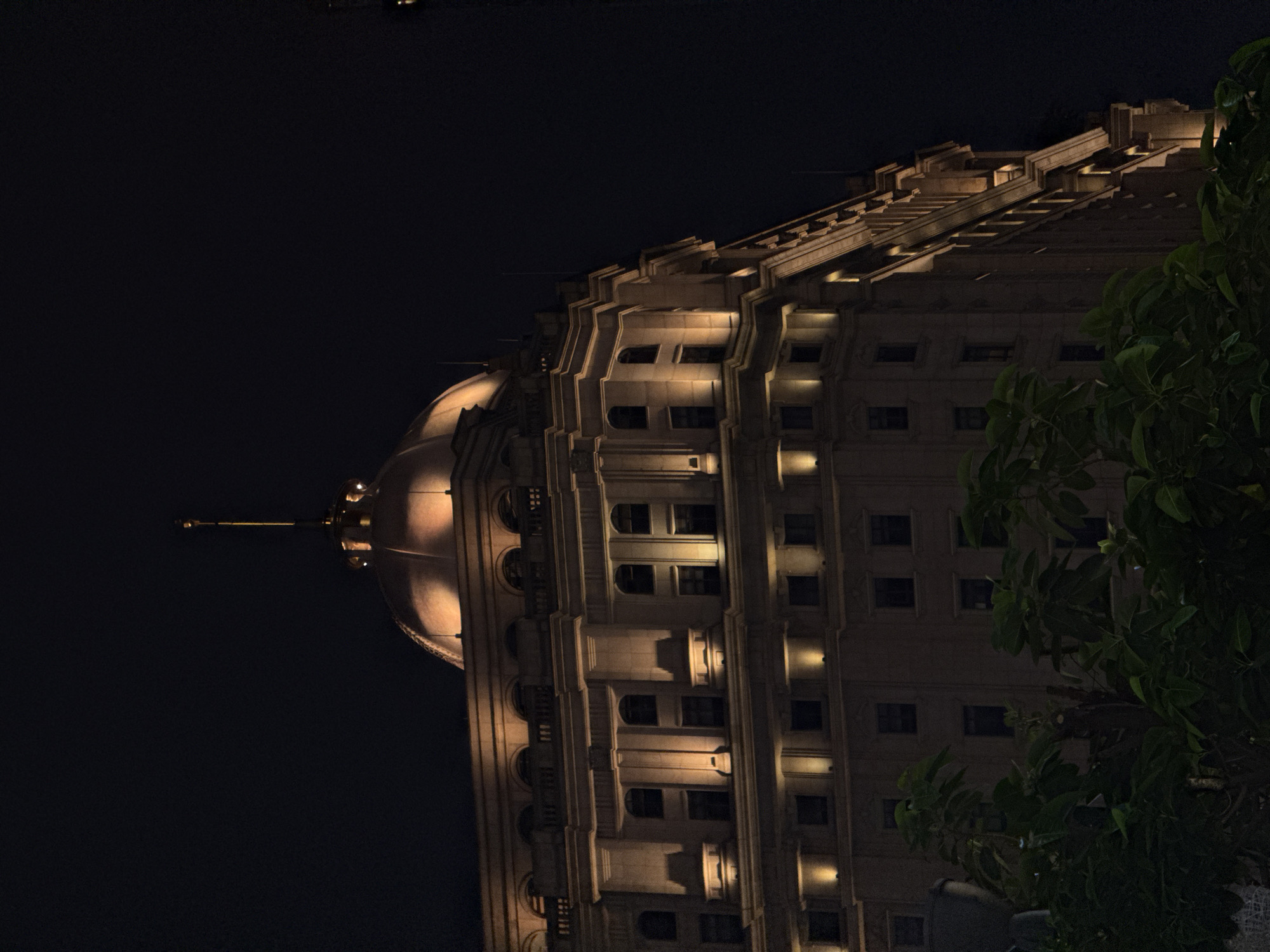 Night shot of a building in Haizhu District, China. The building has a dome at the top and is lit up. There are trees on the right side of the frame. The rest of the background is dark.