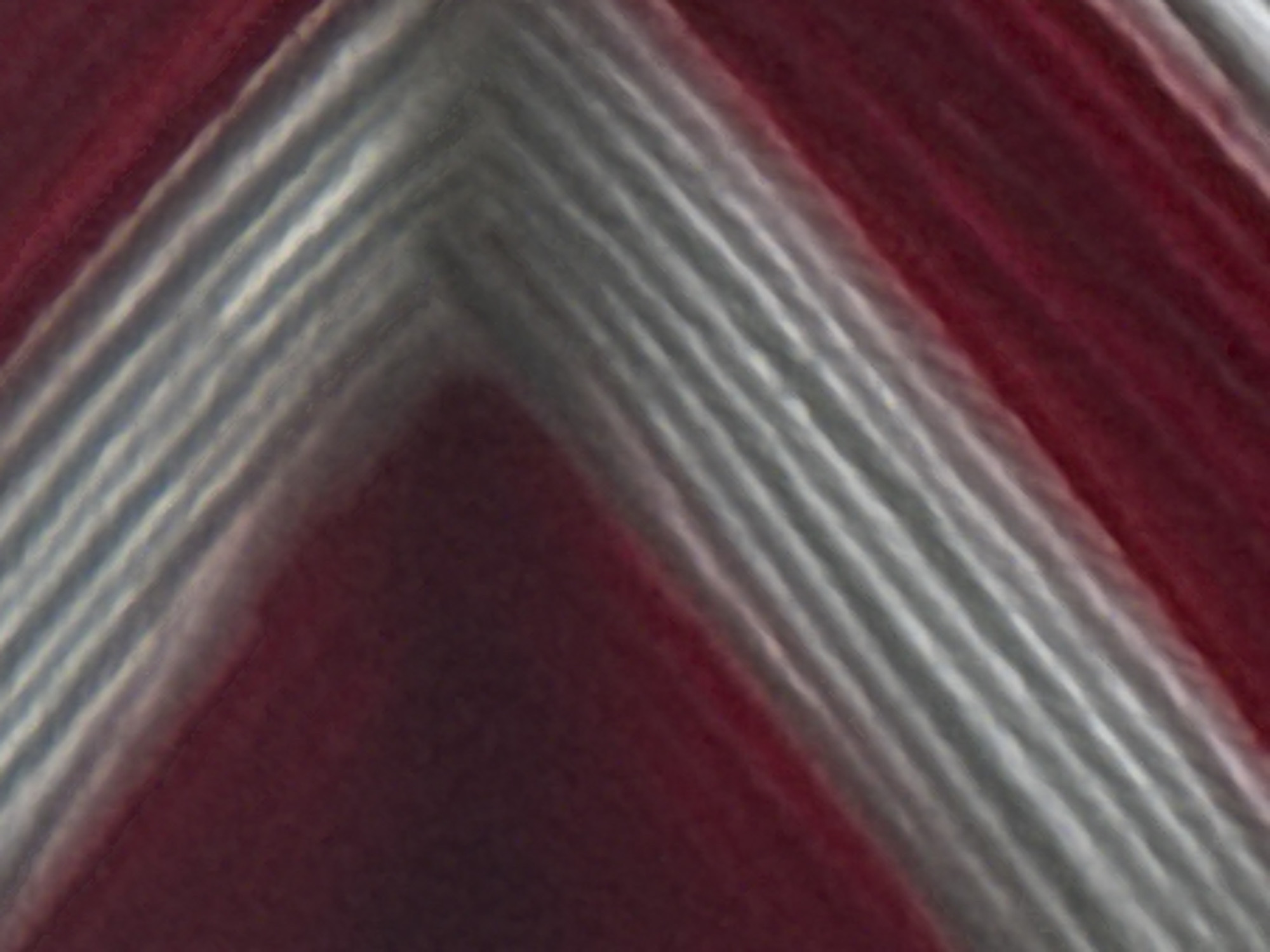 This is a close-up, abstract image of red and white yarn. The yarn is spun in a way that creates diagonal lines and bands of color. The texture appears to be ribbed or woven. The image does not depict any specific location in the city of Skokie, United States of America, nor does it contain any people, subjects, objects, actions, or interactions. The environment is not discernible.