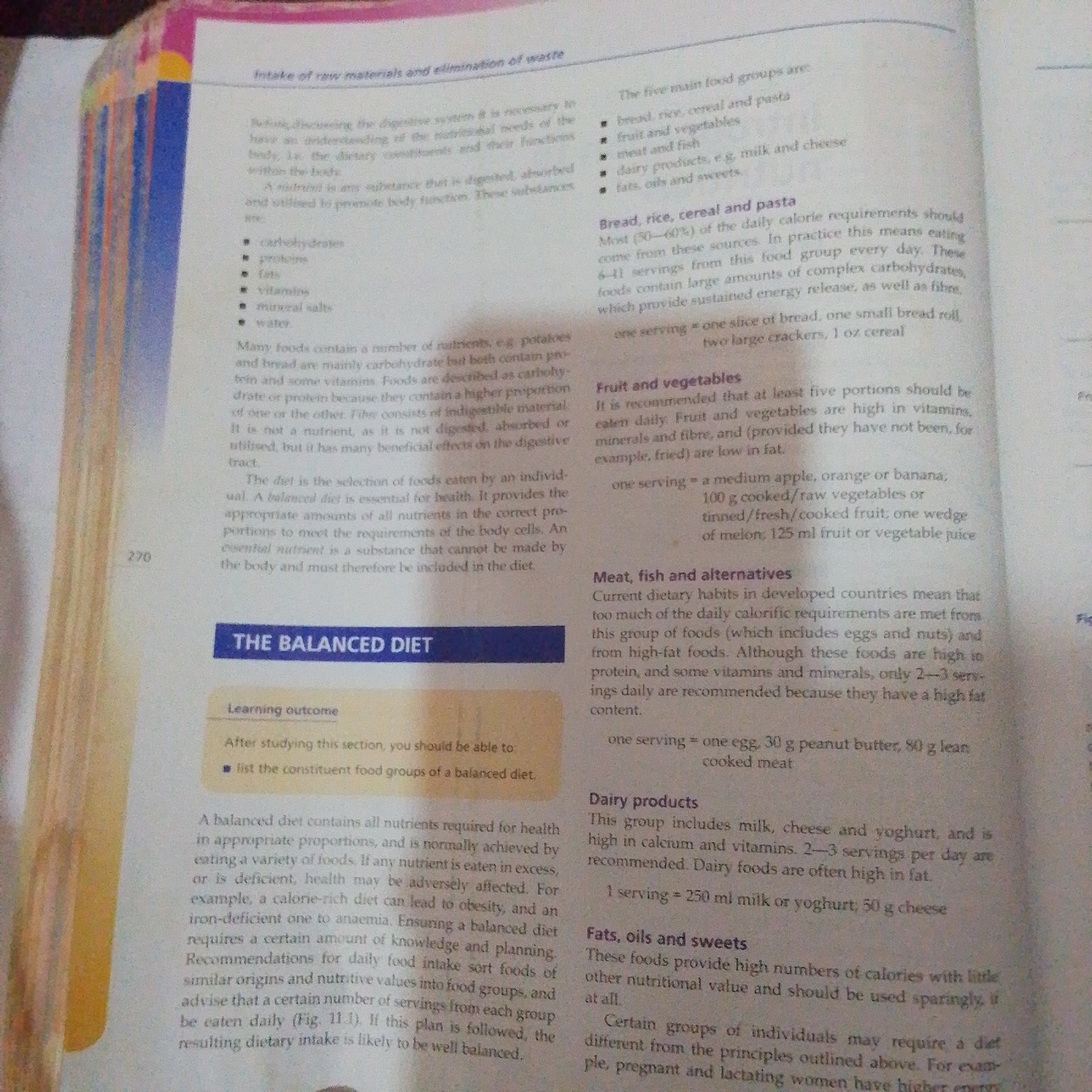 The image shows a textbook page open to a chapter titled "Intake of raw materials and elimination of waste." The text discusses nutrition, food groups, and balanced diets. There is no discernible city, location, or any indication of Jalingo, Nigeria, within the image. The content is purely educational and appears to be from a biology or health science textbook.