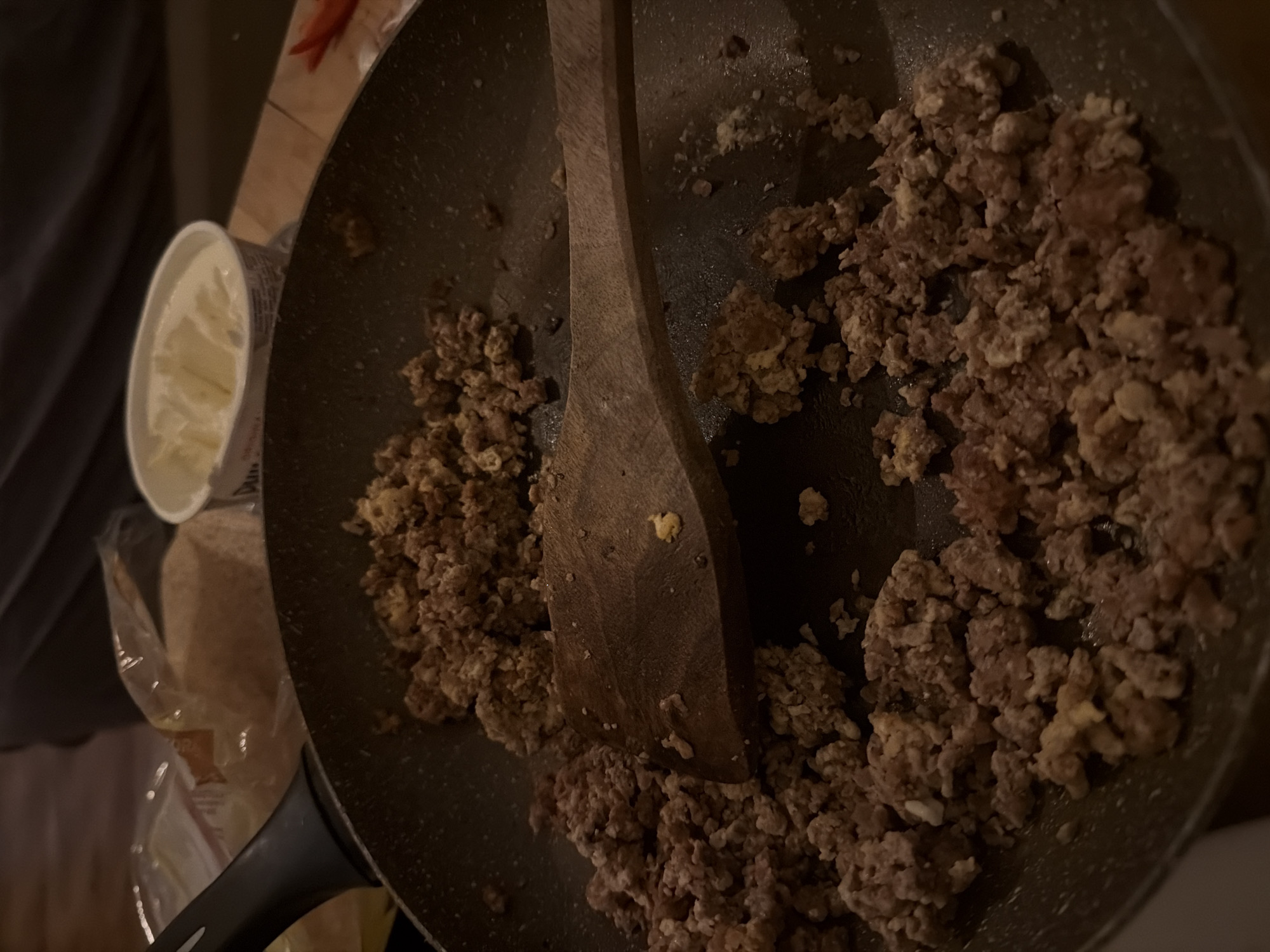 A top-down shot shows a dark frying pan with browned ground meat, a wooden spoon, and a container of what appears to be dairy. It's unclear if the image was taken in Plovdiv, Bulgaria.