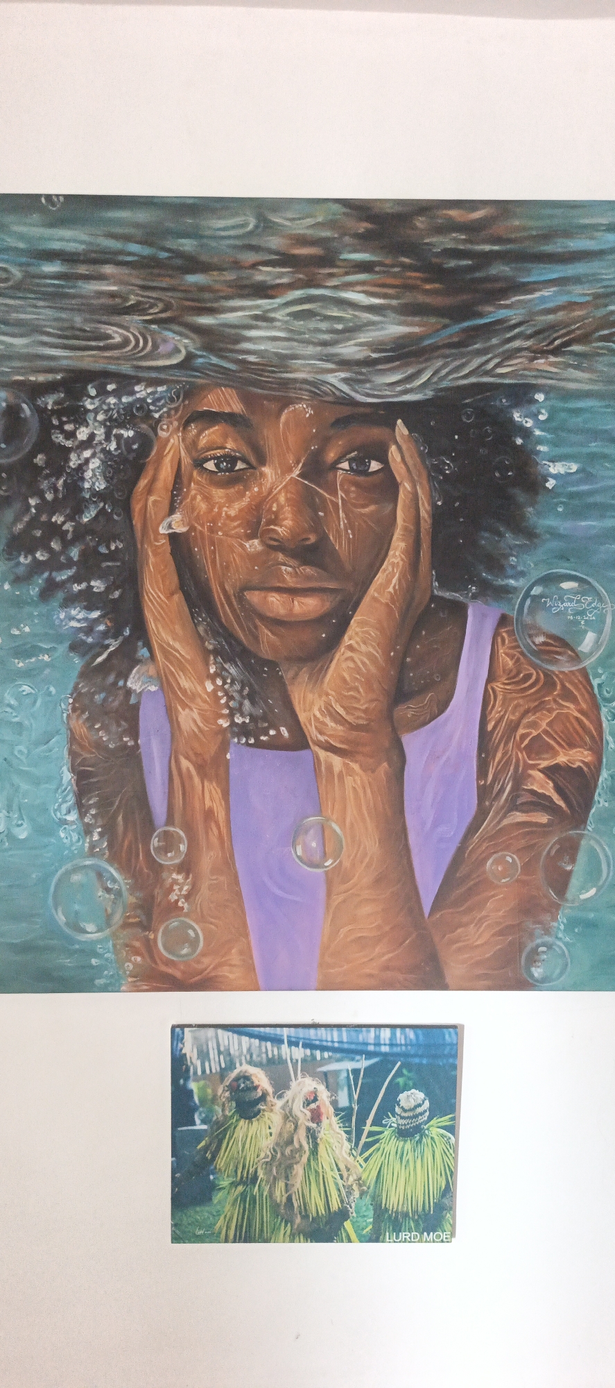 The media file displays two distinct artworks: a painting and a photograph.
The dominant piece is a vibrant, realistic painting of a young Black woman submerged in water. Her face and hands are seen through the turquoise water, with the rippled water surface visible above her head, creating reflections and refractions. Water droplets and patterns appear on her brown skin, and dark, curly hair. Her hands are pressed against her cheeks, and her direct gaze conveys a serious or contemplative emotion. She wears a lilac-colored sleeveless top. Numerous clear, spherical bubbles float around her in the water. A signature "Wizard Edge" and the date "08-12-2020" are visible within one of the bubbles on the right side of the painting.
Below this painting, a smaller photograph shows three figures in elaborate traditional costumes. These figures are covered head-to-toe in long, flowing straw or grass, predominantly light green and tan. Their faces are obscured by distinct masks; two feature shaggy, hair-like textures, while one has a woven, conical headpiece. They stand outdoors, surrounded by lush green foliage, with a dark, mesh-like structure visible overhead, possibly a canopy or shading. These figures appear to be participants in a cultural event or ceremony, possibly masqueraders, common in regions like Akwanga, Nigeria. The text "LURD MOE" is printed at the bottom right corner of this photograph.