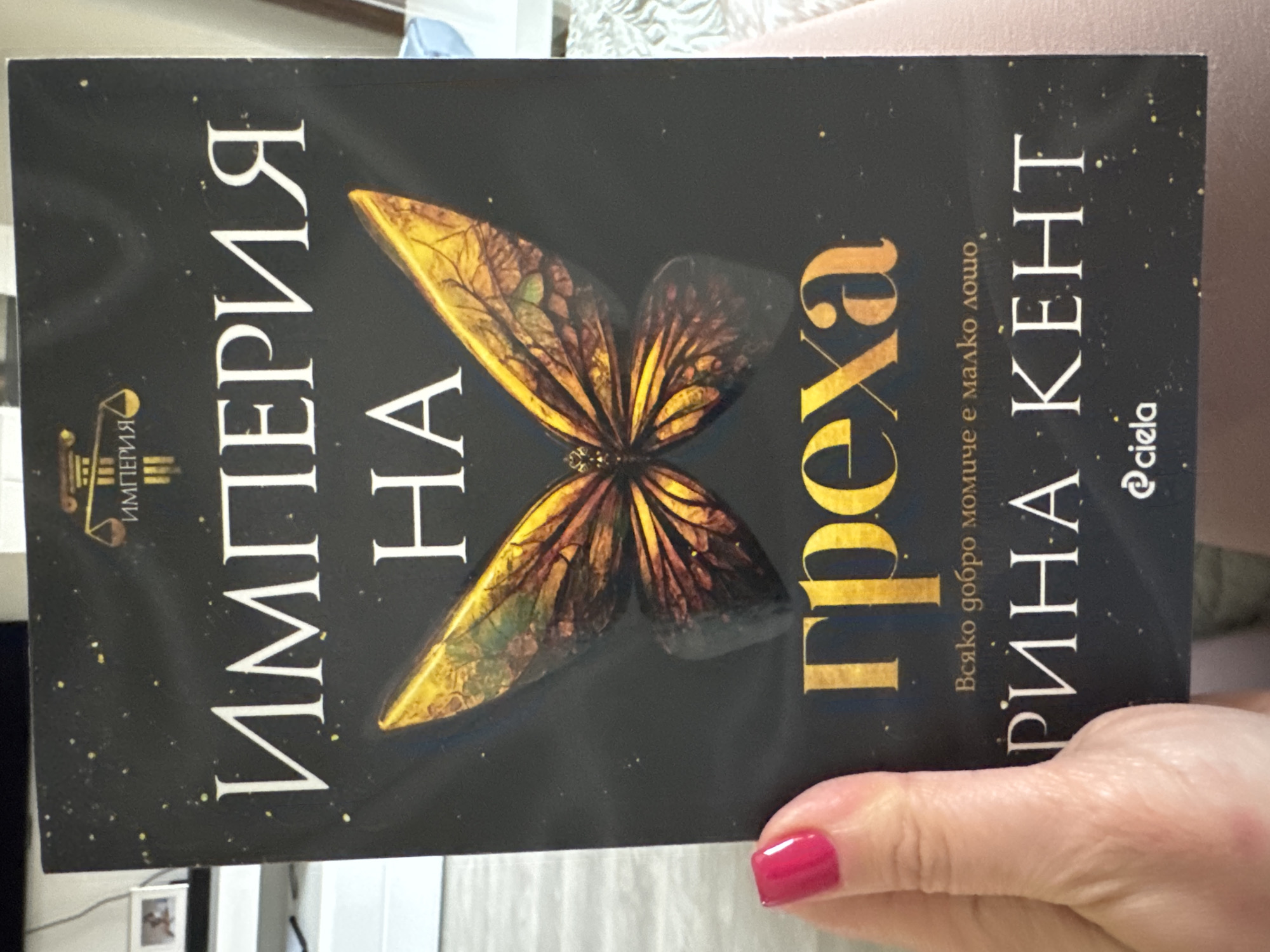 The image shows a book cover. The title, "Империя на греха," is prominently displayed, and the author's name, "Рийна Кент," is visible along with the publisher "Ciela". The book cover features a butterfly image. The title and the author's name suggest that the book is in Bulgarian. While the text is in Bulgarian, the information available in the image does not specify the location of the image was captured. Therefore, I cannot confirm whether it was taken in Sofia, Bulgaria, or any other location.