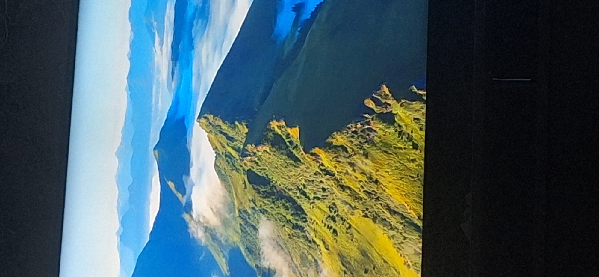 This is an aerial photograph of a mountain range. The mountains are covered in green vegetation and some are shrouded in mist. In the distance, other mountain ranges are visible, fading into a hazy blue sky. The overall impression is one of vastness and natural beauty. There is no visible presence of the city of Bila Tserkva, Ukraine in this image.