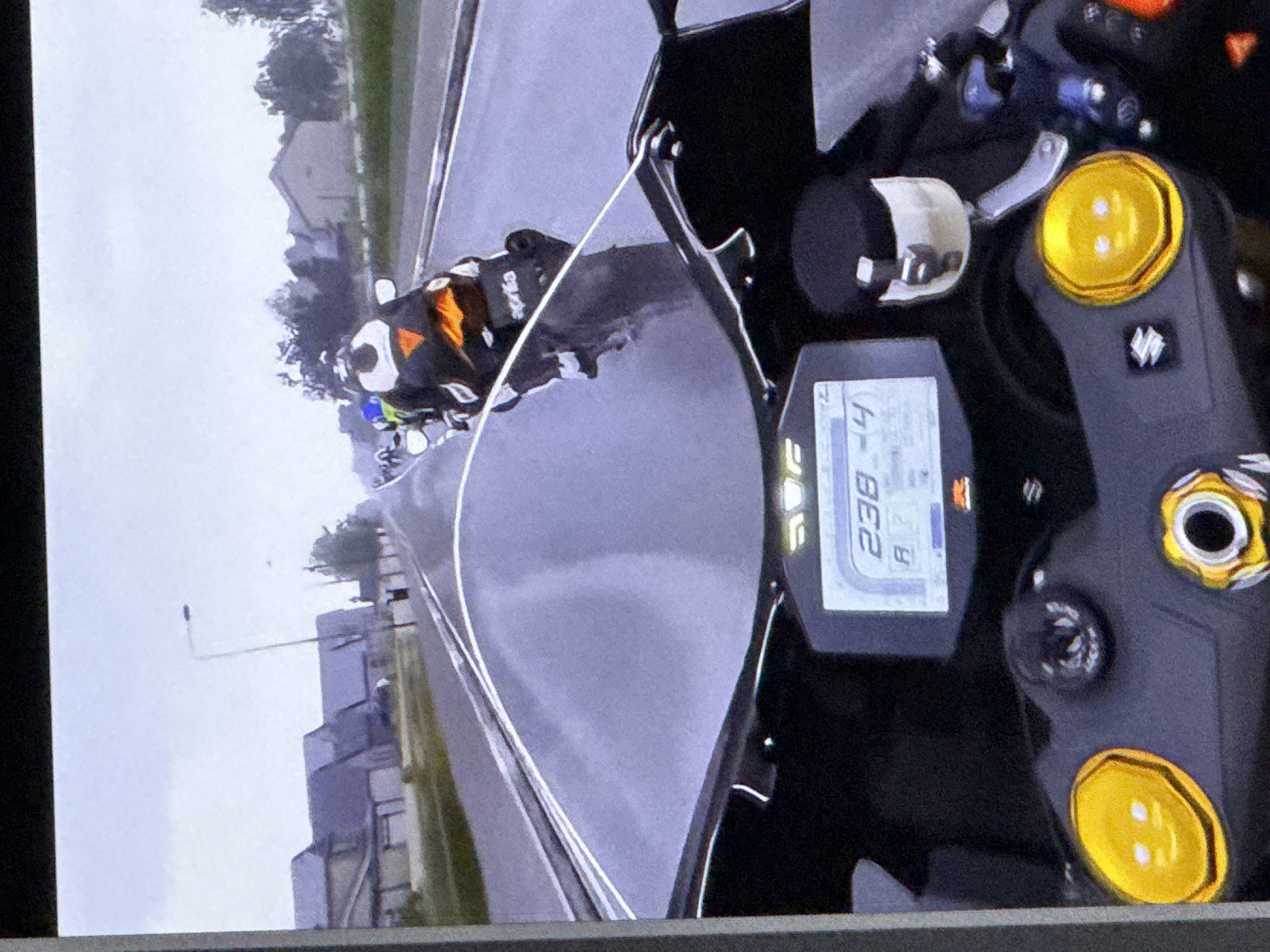 This media file shows a first-person perspective of someone riding a motorcycle. The rider is wearing a black and orange racing suit with a white helmet that has a black and white design. The motorcycle's dashboard is visible, displaying the number "238". The scene is set on a paved road, likely a race track, with buildings and trees visible in the background. The weather appears overcast, and the road surface is wet, suggesting it may have recently rained or is about to. The overall impression is that of a dynamic and fast-paced activity. The visible text on the dashboard is "238" and an indicator that looks like "R". The setting is consistent with a location in Cahul, Moldova.