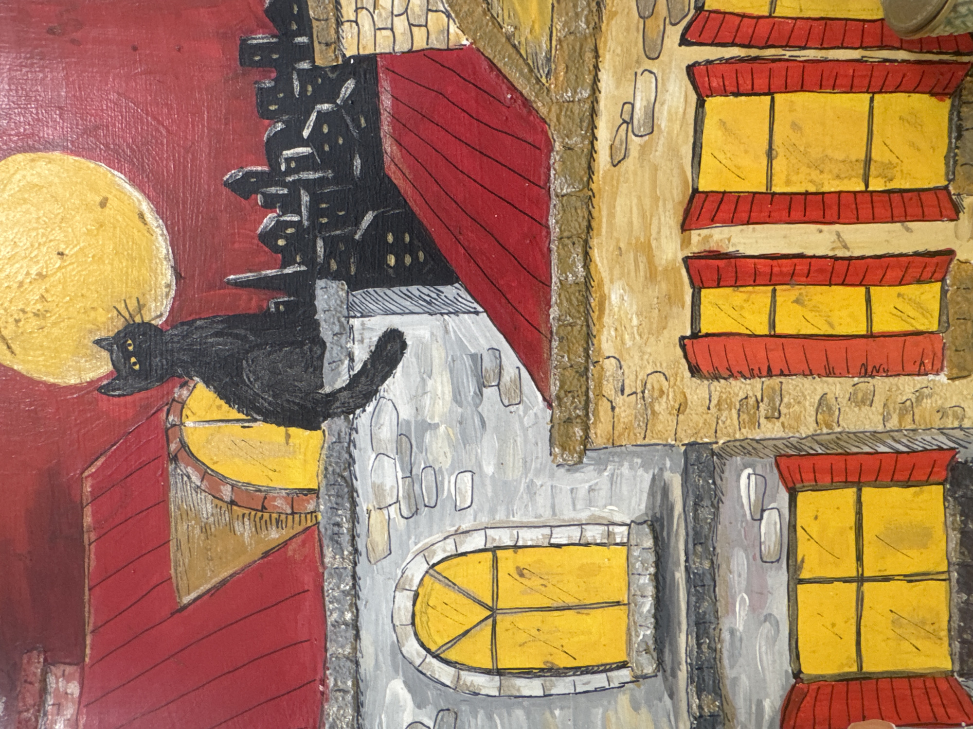 The image is an artistic rendering of a night scene in what appears to be a European-style town, though a specific connection to Ramat Gan, Israel, is not evident. Dominating the left side is a large yellow moon against a red sky. A black cat sits near an illuminated, rounded window. In the background are depictions of buildings with varying architectural styles, including red-roofed structures and grey stone buildings with arched windows. Several windows glow yellow, suggesting interior lighting. The overall style is somewhat whimsical and illustrative.