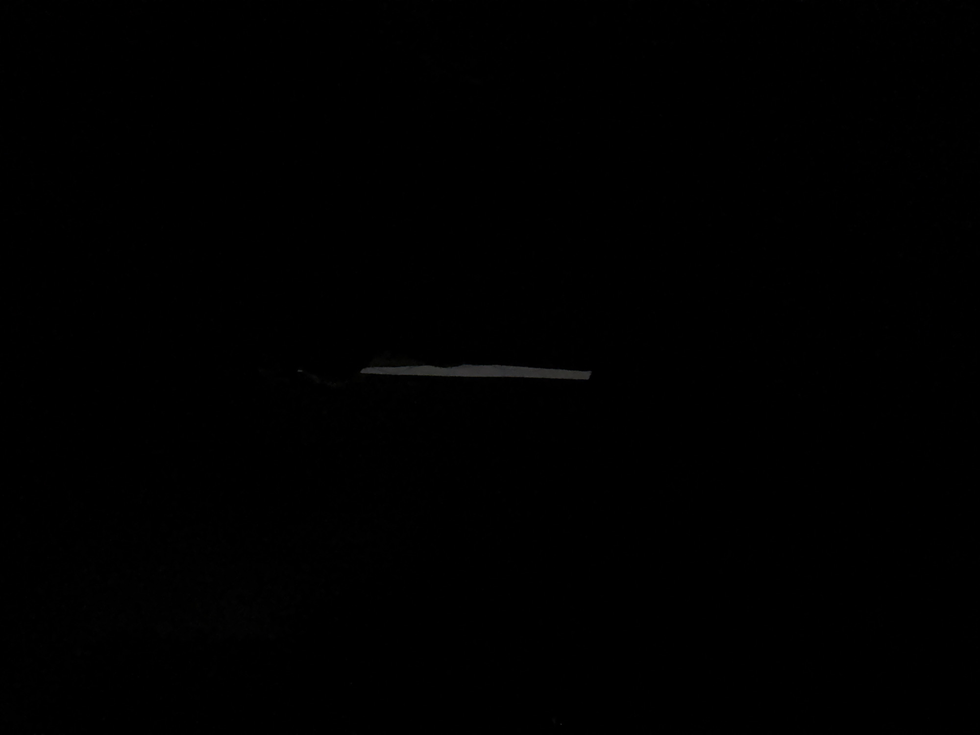 The image is a low-light photograph, possibly taken at night. In the center, a horizontal, elongated gray object is barely visible against the black background. Based on the prompt mentioning Chuprino, Russia, it is reasonable to infer this might be a street or road segment. Given the lack of detail, no further elements or actions can be determined.