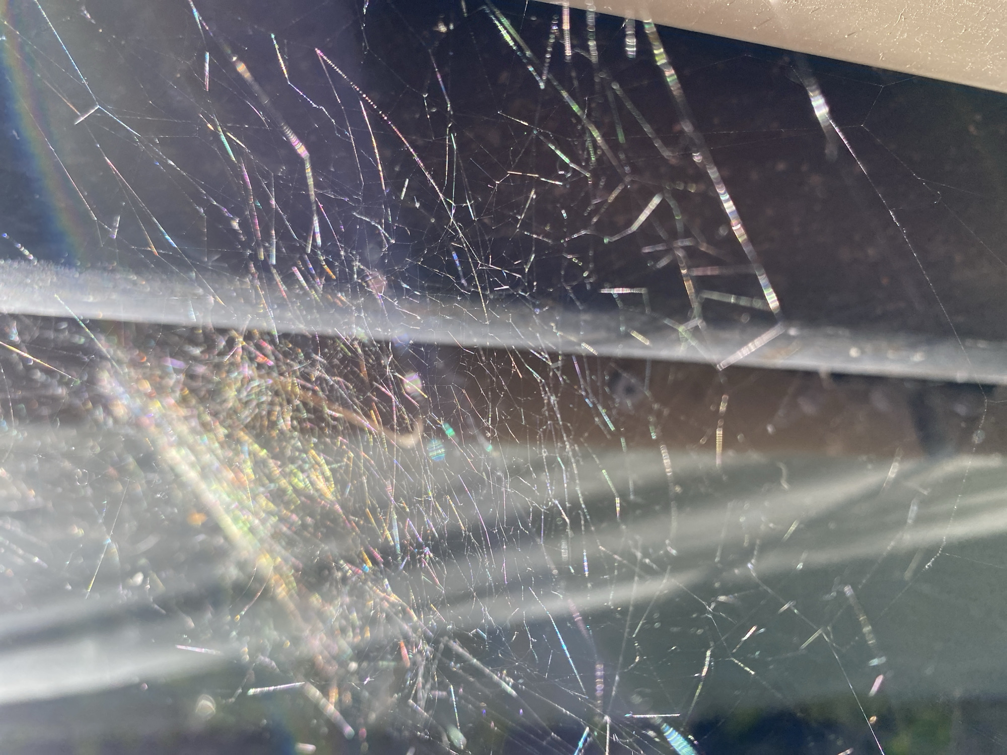 The image shows a spiderweb with iridescent colors. The web is located under the eaves of a building. The location in the city of Chaikovsky, Russia, is unknown.