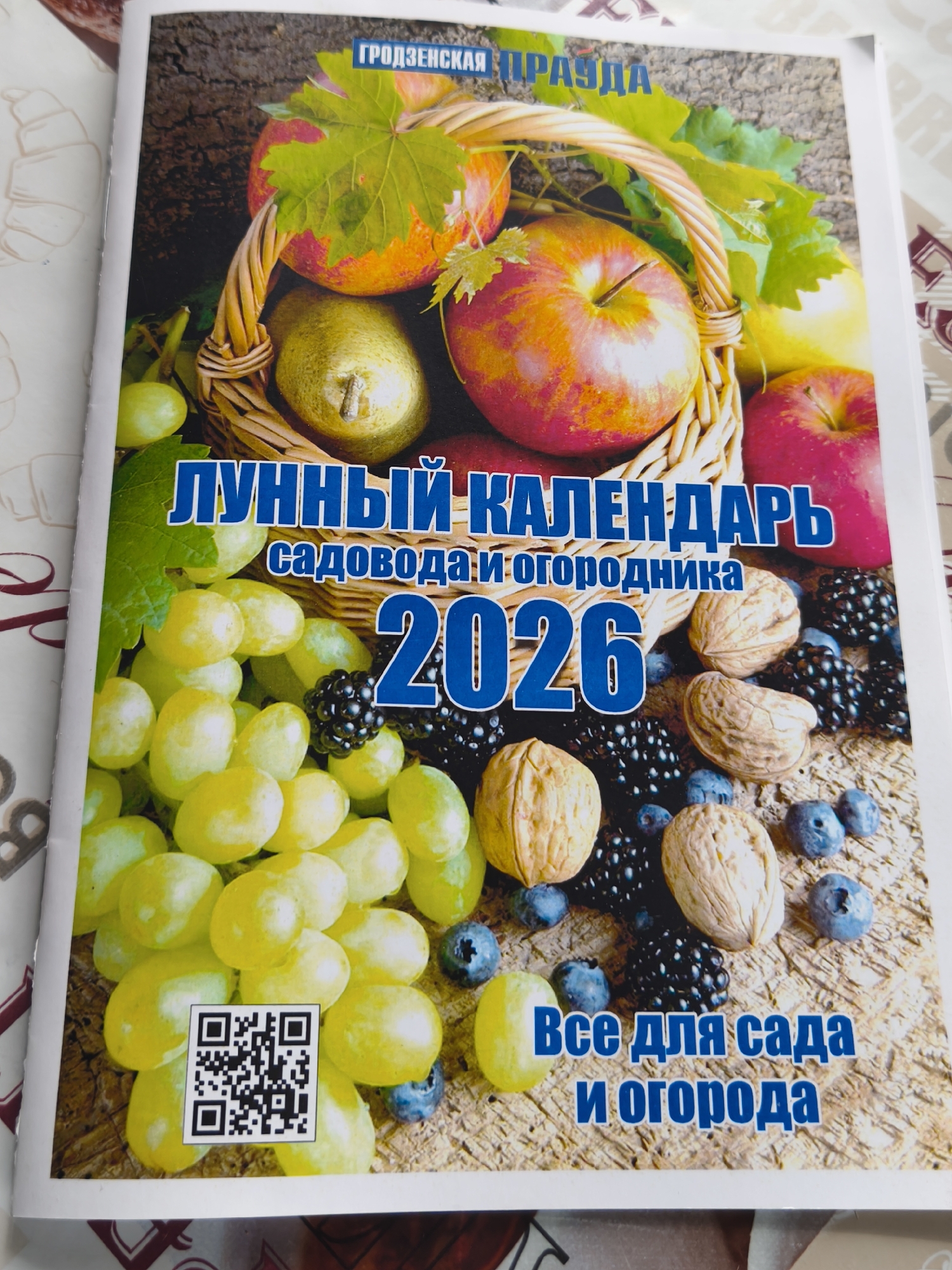 The image shows the cover of a magazine titled "Лунный Календарь садовода и огородника 2026," which translates to "Lunar Calendar for Gardeners and Gardeners 2026". The magazine appears to be published by "Гродзенская Правда" (Grodno Truth).
The cover features a basket filled with fruit, including apples and pears, as well as grapes, blueberries, blackberries, and walnuts scattered on a wooden surface. A QR code is also visible on the cover. The bottom of the cover says "Все для сада и огорода", which translates to "Everything for the garden".
There is no indication of the location being Парэчча, Belarus.