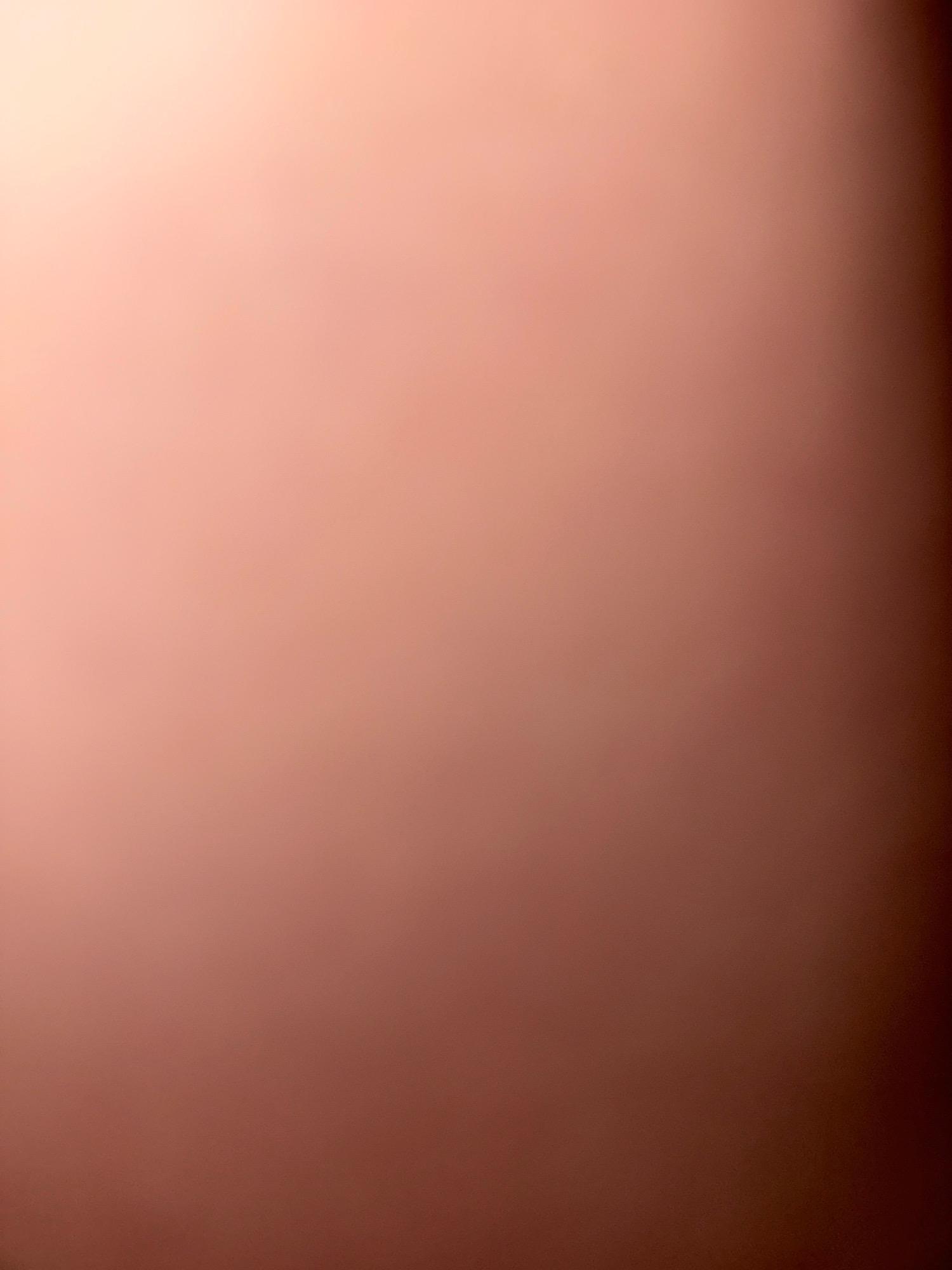 The image is a photograph of a plain, slightly textured surface with a gradient of warm, peachy-pink to dark brown tones. There are no discernible objects, people, or environmental details visible, making it an abstract or out-of-focus shot. It is not possible to determine the location in the city of Zavolzhye, Russia, or any other specific details from this image.