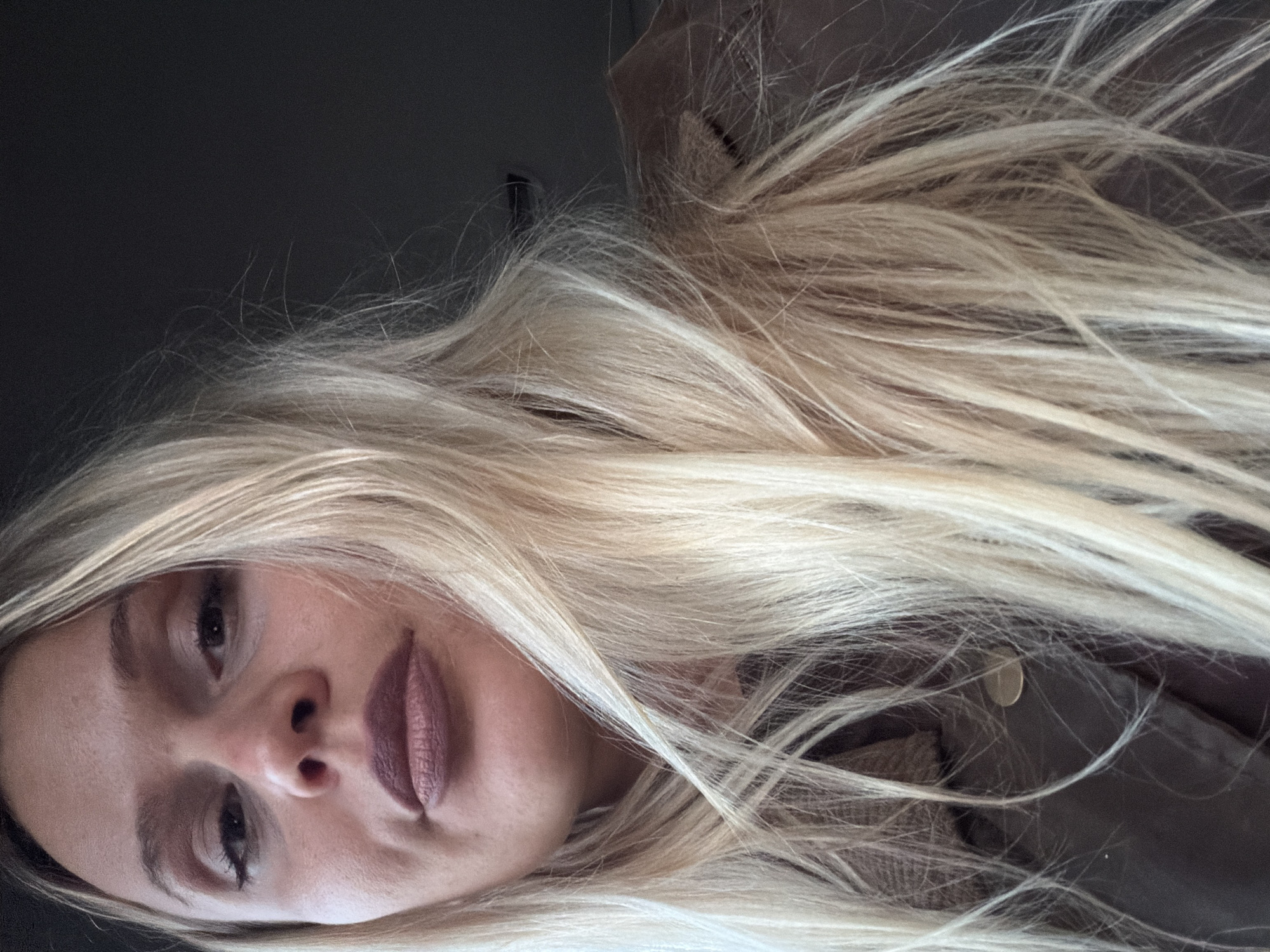 The image shows a woman with long blonde hair. Her face is visible, and she has light skin, brown eyes, and mauve lipstick. Part of a brown jacket is also in the frame. The location is not discernible from the image. The city of Sarapul, Russia is not suggested by the imagery.