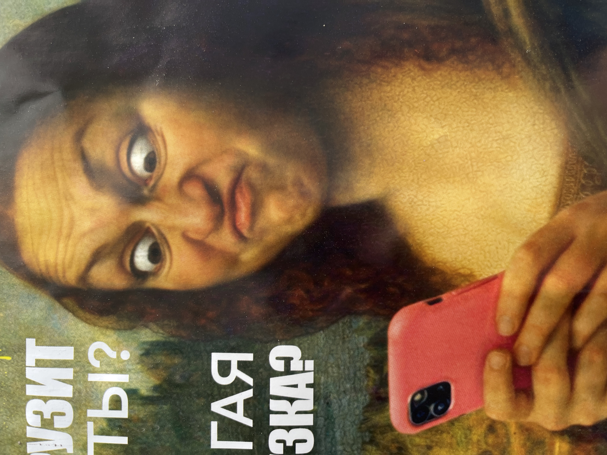 The image features a satirical take on the Mona Lisa, with a distorted, comical expression on her face. She is holding a pink smartphone, seemingly taking a selfie. The background resembles the classic Mona Lisa painting, albeit with visible imperfections. The text "УЗИ ТЫ? ГАЯ ЗКА?" is visible in the lower left of the image. While the image is likely a digitally altered photograph, there is no information to conclude that the image was taken in Krasnoyarsk, Russia.