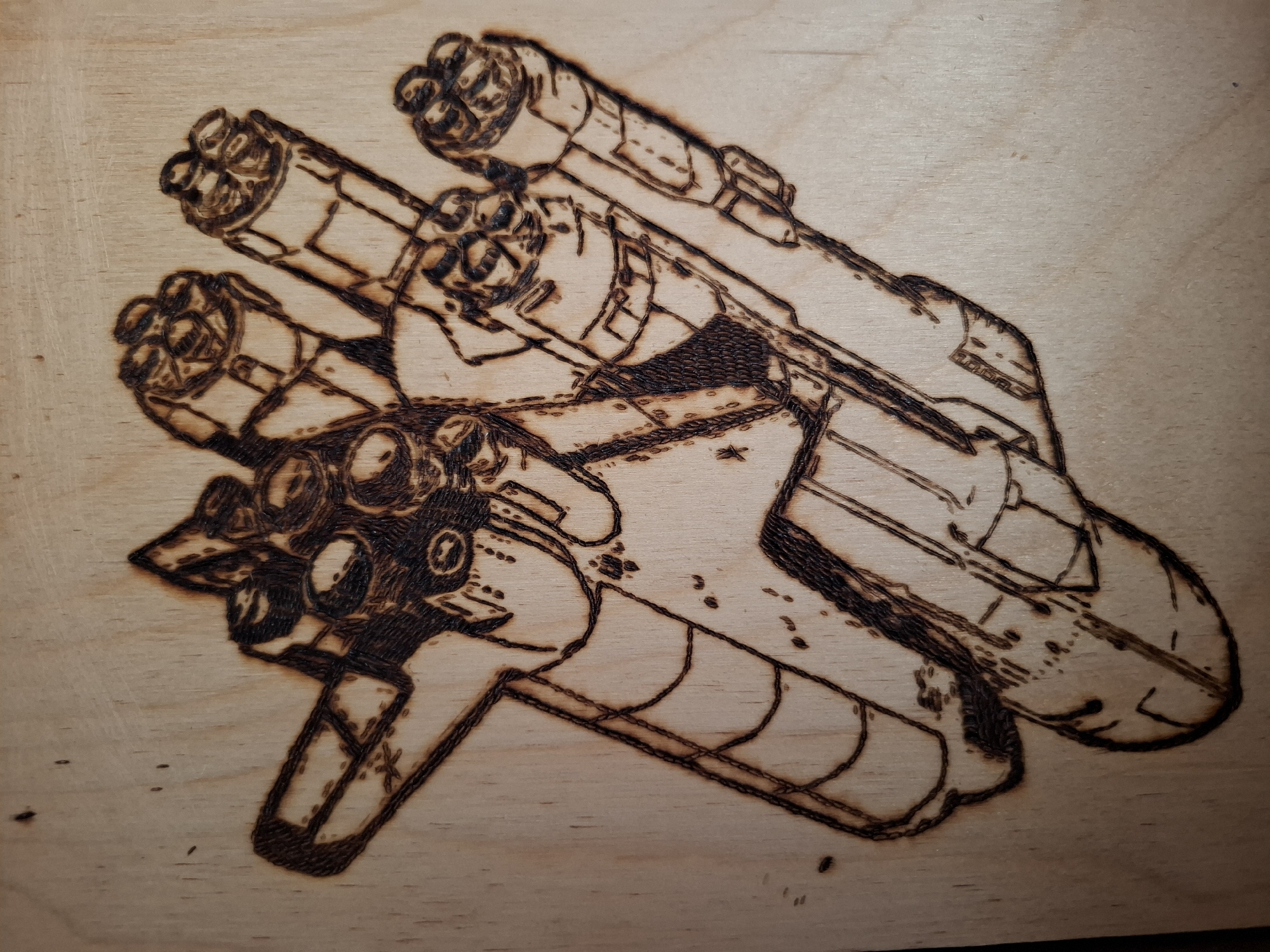 The image shows a wood-burned illustration of a futuristic vehicle, possibly a spacecraft or weapon. The vehicle has multiple cylindrical components with intricate detailing, resembling engines or cannons. The illustration is on a light-colored wooden surface. The image does not contain any information related to the city of Амзя, Russia.
