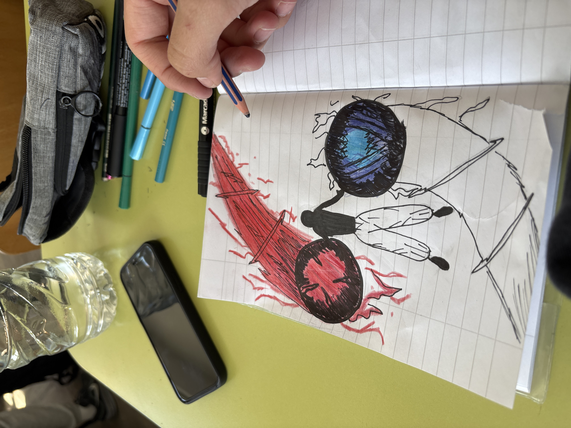 A hand holds a blue and brown pencil above a drawing of a moth on lined paper. The moth drawing has blue and red colored eyes, black body, and partially drawn black and white wings. To the left of the paper are a gray pencil case, several colored pencils, a black marker, a bottle of water, and a black smartphone on a light green surface. The specific location in the city of Zlatograd, Bulgaria is not discernible from the image.