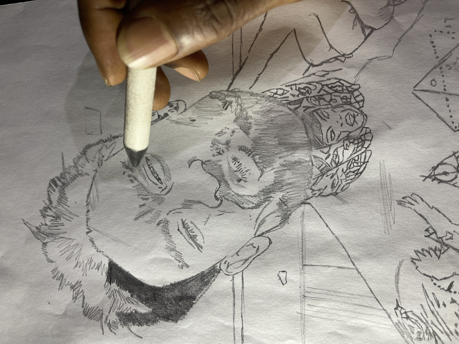 The image displays a close-up, overhead view of a pencil drawing on white paper, currently in progress. The drawing portrays a stylized male figure from the chest up. The subject features spiky hair with dark shading on the left side, a furrowed brow, narrow eyes, a prominent nose, exaggerated lips, and a full beard. Extensive, complex tattoos are visible on the figure's neck, including a discernible stylized face. Additional tattoo work, notably a symbol resembling a pyramid with an eye, is present on the upper chest area. A dark-skinned human hand enters the frame from the right, holding a white, cylindrical blending stump. The tip of the blending stump is positioned directly on the drawn subject's left eyebrow, indicating an active shading or blending process. The immediate environment consists solely of the white paper surface. There are no visual elements within the image to identify its location as Jos, Nigeria.
