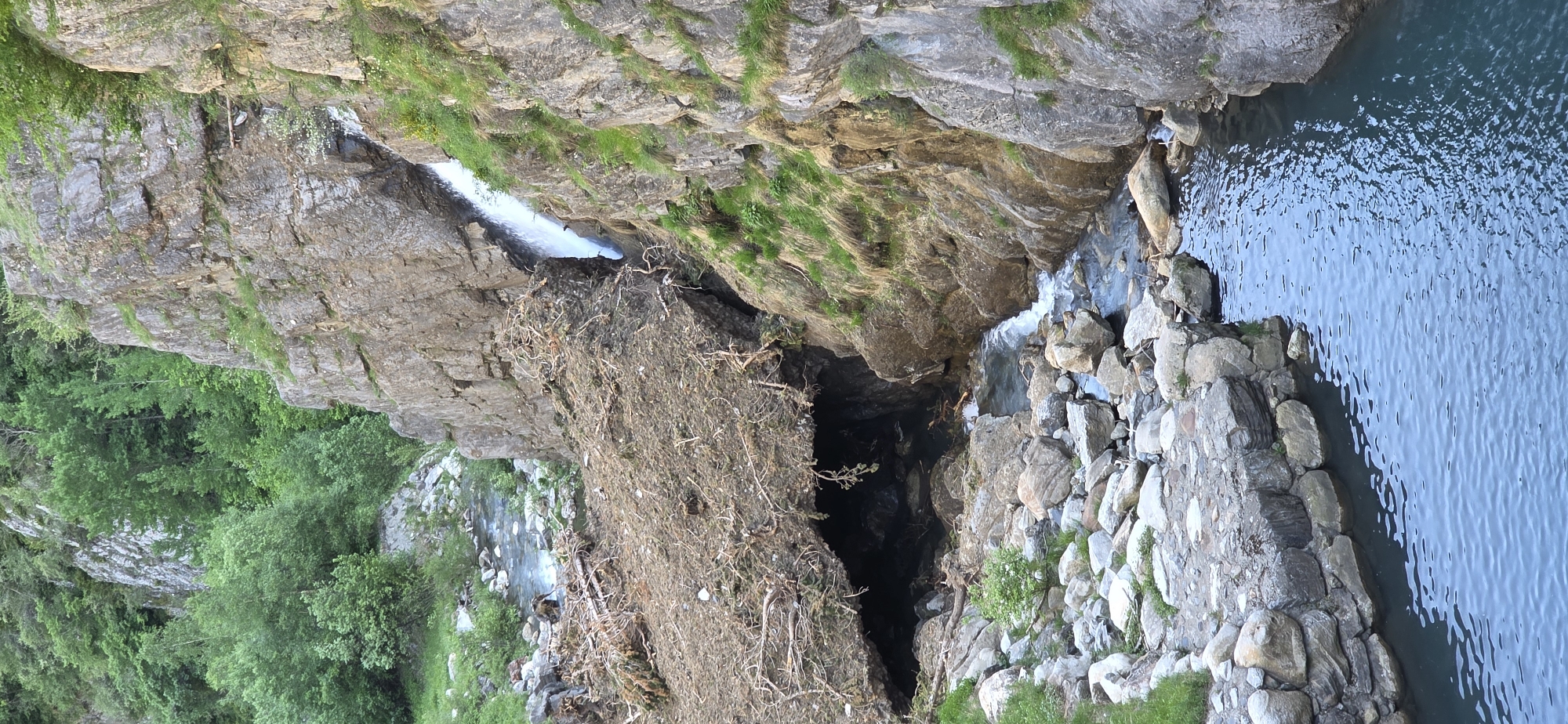 The image shows a narrow, rocky gorge with water flowing through it. The location appears to be a natural area outside of a city, characterized by steep, rocky banks, dense foliage, and water. The image contains various elements of a natural environment, including exposed bedrock, small waterfalls, and a pool of water. The scene is in Benasque, Spain.