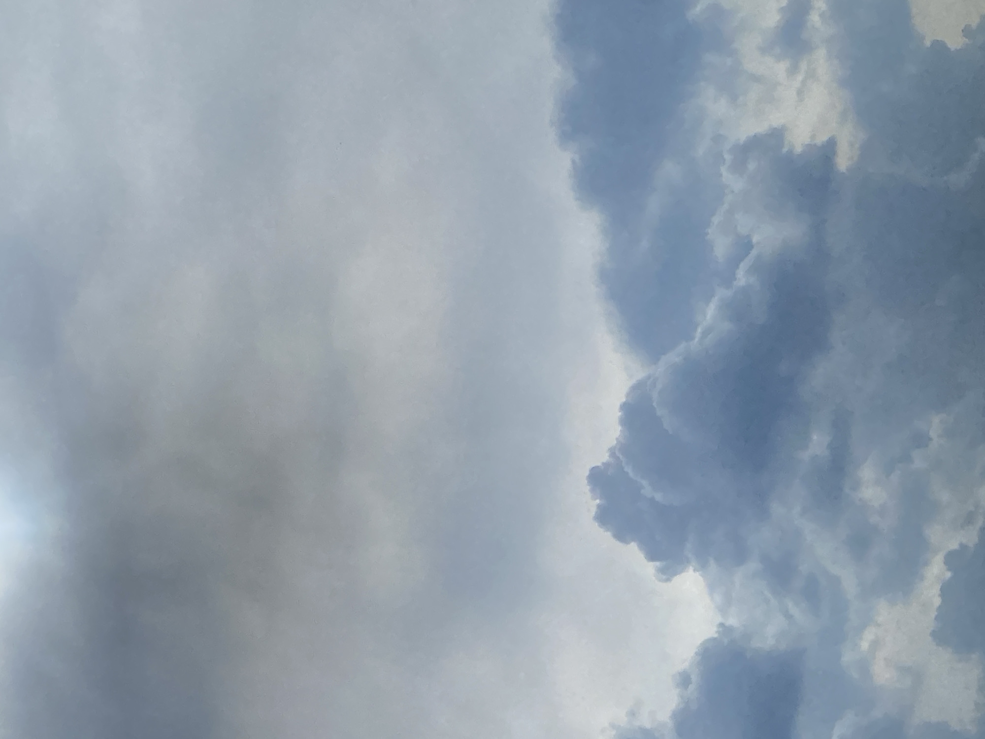 The image shows a cloudy sky in what appears to be daylight. The left side of the image is filled with hazy, lighter gray clouds, while the right side features denser, darker, and more textured cloud formations. The overall color palette is dominated by shades of gray and blue. There is no indication of any specific objects, subjects, or interactions. There is no proof that this image was taken in the city of Talitsy, Russia.