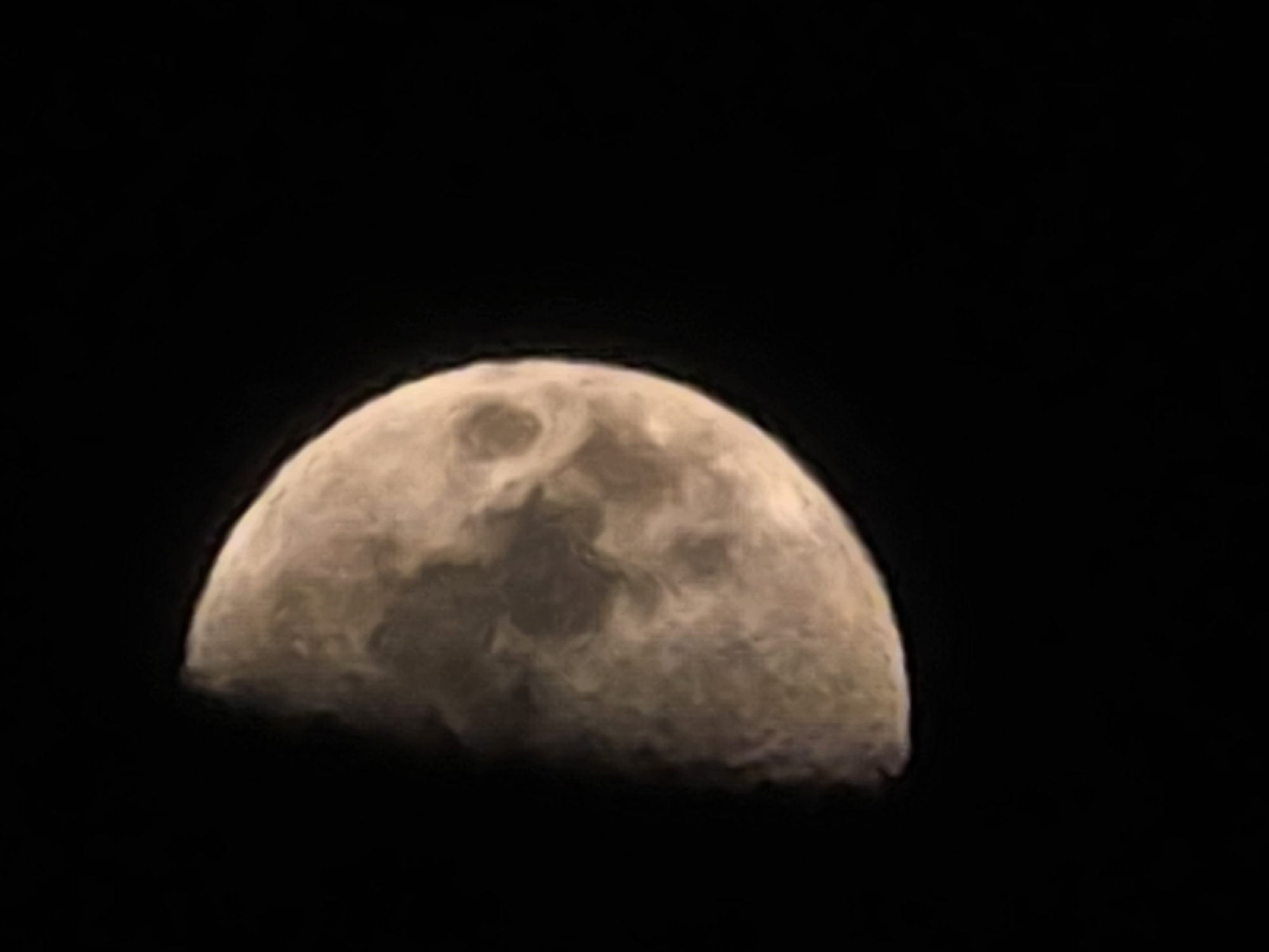 The image shows a close-up view of the moon against a black background. The moon is illuminated from the right, with approximately half of its surface visible. The visible portion of the moon displays craters and surface features with varying shades of gray and brown. The illumination creates a clear distinction between the lit and unlit portions of the moon. There are no discernible elements of the city of Yambol, Bulgaria, within the image.