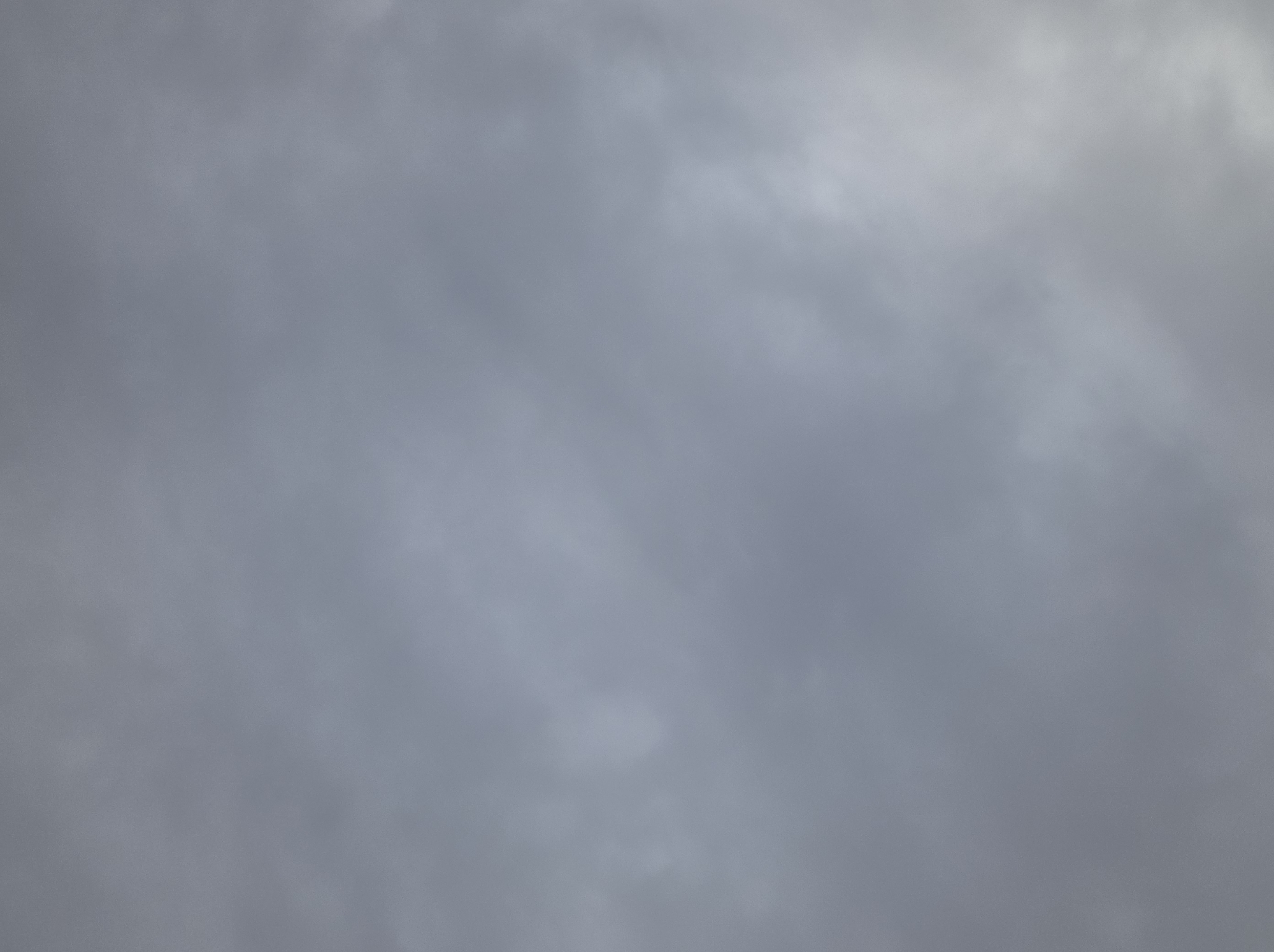 A cloudy sky is visible, with varying shades of gray and white indicating the presence of clouds. The image is a full frame shot, with no discernible foreground or background elements, suggesting it was taken from an open area. The lighting suggests it is daytime, but the cloud cover prevents direct sunlight. The specific location within Tokmok City, Kyrgyzstan, cannot be determined from the image alone as it only depicts the sky.