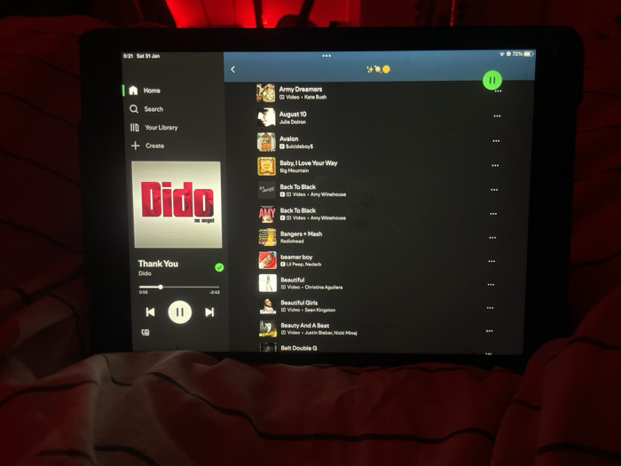 A tablet displays the Spotify app in dark mode, showing a playlist. Currently playing is "Thank You" by Dido. The playlist includes songs such as "Army Dreamers" by Kate Bush, "August 10" by Julie Doiron, "Avalon" by Suicideboy$, "Baby, I Love Your Way" by Big Mountain, and two tracks of "Back To Black" by Amy Winehouse. Also listed are "Bangers + Mash" by Radiohead, "beamer boy" by Lil Peep, and multiple artists like Christina Aguilera, Sean Kingston, Justin Bieber, and Nicki Minaj. The tablet shows the time as 0:21 on Saturday, January 31, with 72% battery.