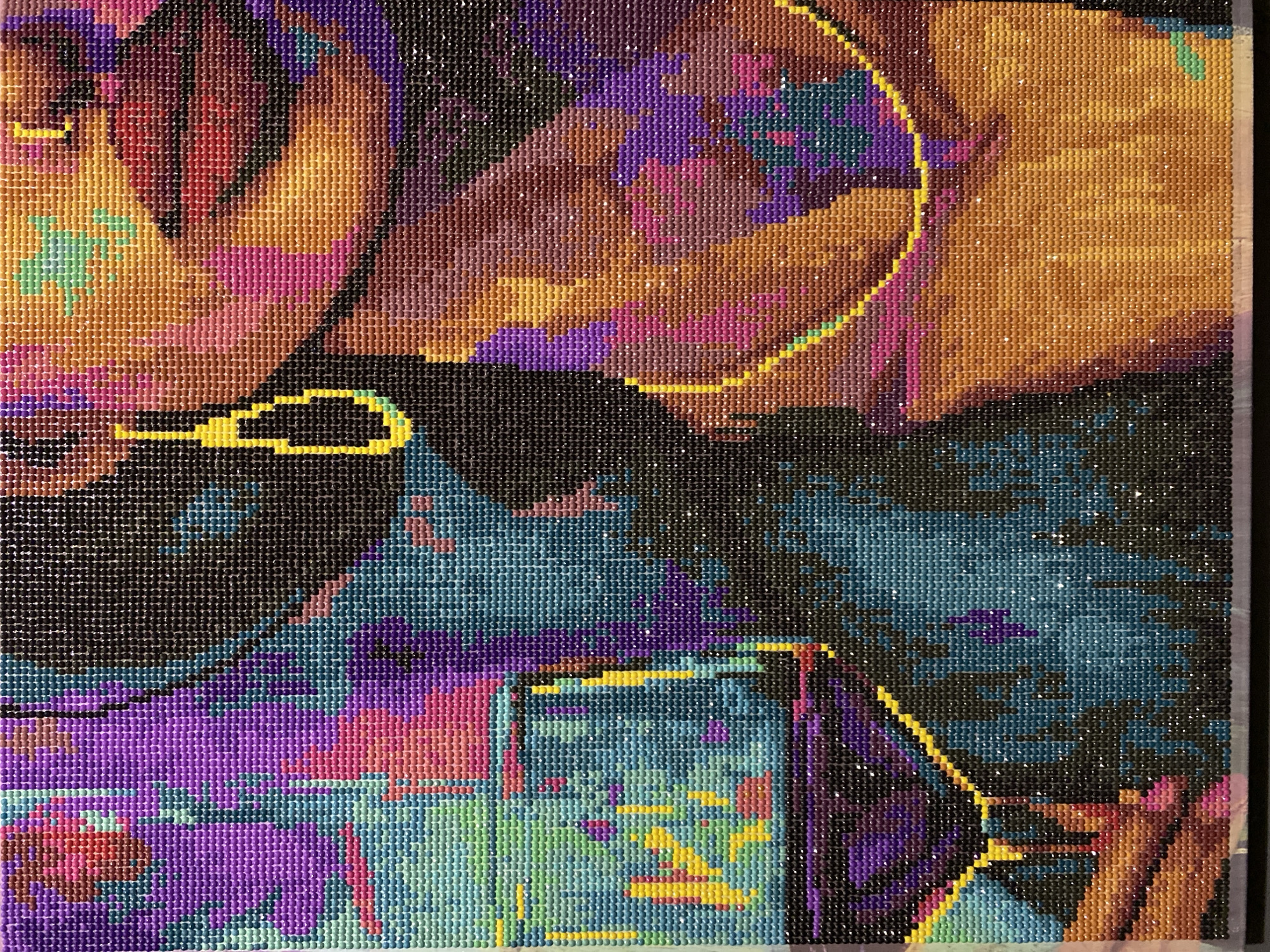 The image is a close-up of a diamond painting. The painting depicts a stylized portrait of a woman with vibrant colors. The woman has dark hair, and is wearing a yellow earring and necklace. She appears to be holding a glass of red wine. The background is abstract and colorful, with shades of purple, blue, and green. The diamond painting is the subject of the image, and there is no indication of its location in Tambov, Russia, or any other city.