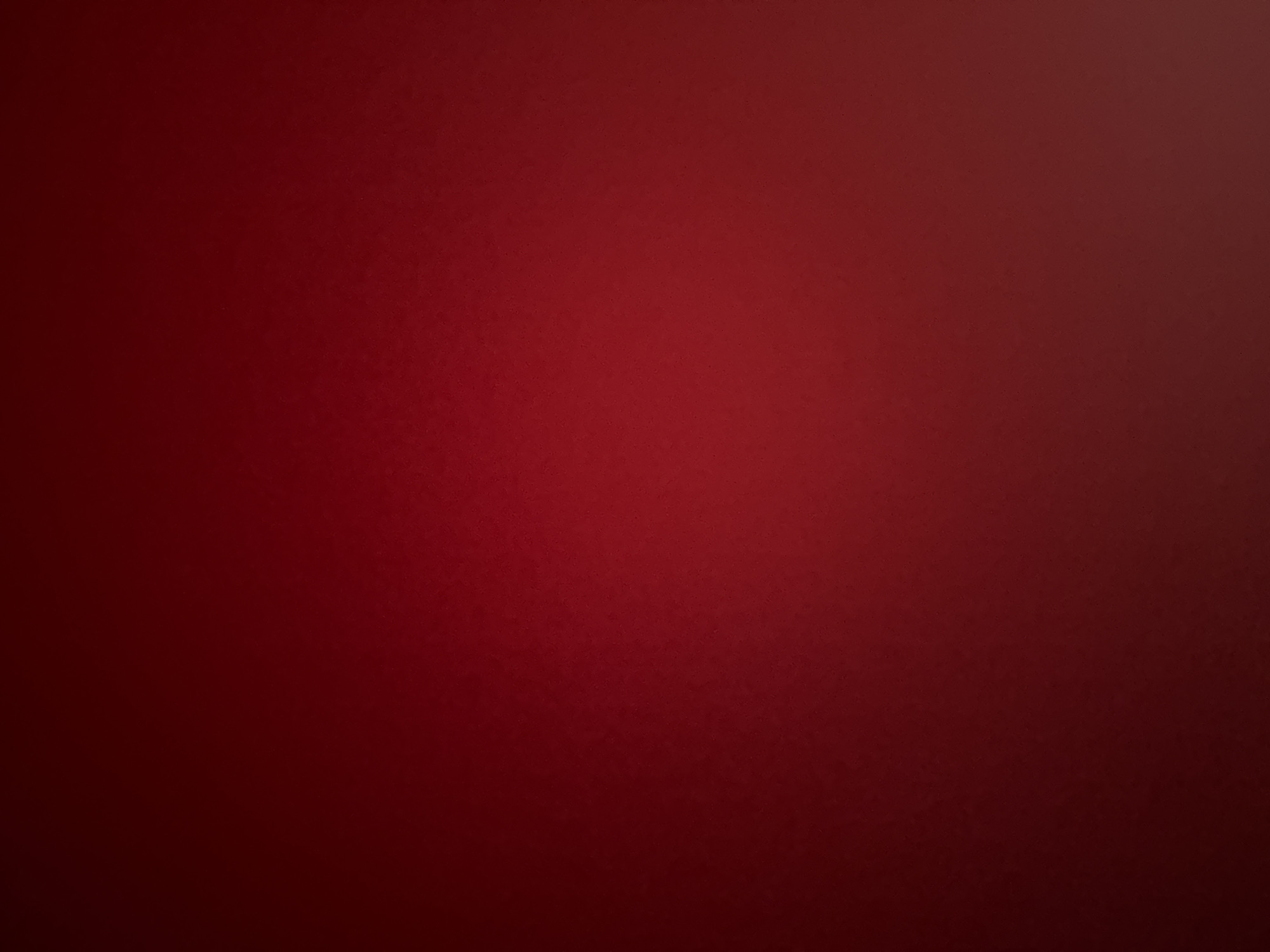This is a photograph of a plain red surface with a gradient effect, likely a wall or fabric. There are no discernible objects, people, or actions depicted in the image. The lighting creates a subtle shift in color, appearing darker on the left and lighter towards the bottom right. The image does not provide any visual information related to the city of Varna, Bulgaria.
