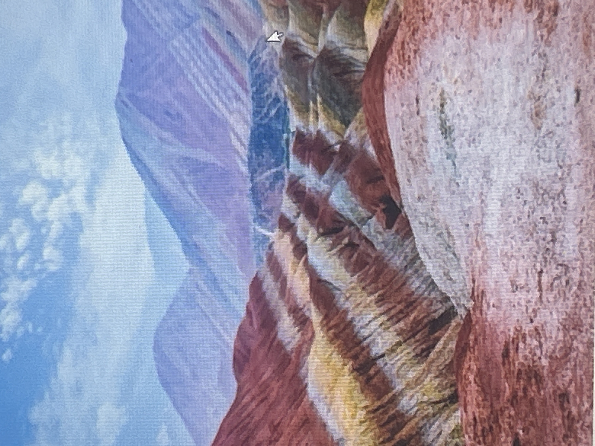 The image shows a landscape with colorful, layered mountains under a cloudy blue sky. The mountains exhibit distinct bands of red, yellow, white, and purple hues, suggesting geological formations. In the mid-ground, there are undulating hills and valleys, also displaying the characteristic banding. The foreground features a reddish-brown, rocky terrain. The image does not depict any elements that would suggest a location within the city of Sofia, Bulgaria, or any urban environment.