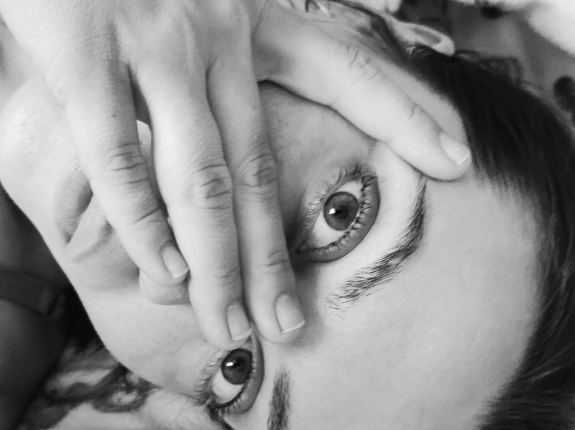 A close-up, black and white image shows a person's face obscured by a hand. The person's eyes are visible between the fingers. The person appears to be lying down, and the background is slightly blurred. The location in the city of Chaikovsky, Russia, is not possible to determine from the image alone.