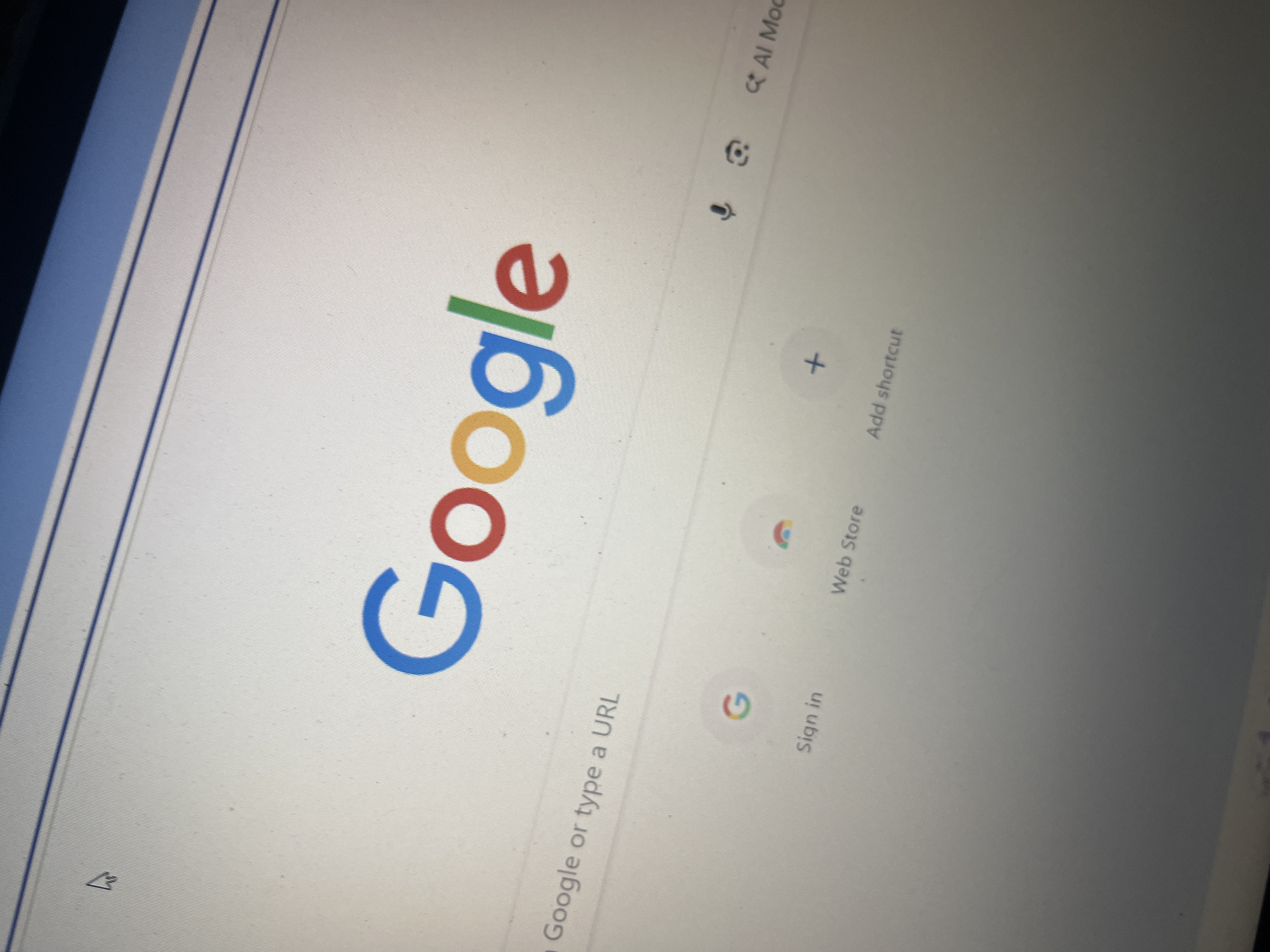 The image shows a close-up of a computer screen displaying the Google homepage. The Google logo is prominent in the center of the screen, with its signature blue, red, yellow, and green colors. Below the logo, there is a search bar that reads "Search Google or type a URL." Further down, there are icons for "Sign in," "Web Store," and "Add shortcut." A microphone icon and an image icon are also visible. The screen appears to be a monitor, and the background is a light gray with a subtle texture. The top of the image shows the blue bar of a web browser window. There are no people visible in the image, and the scene is a digital interface. The provided location of Santa Ana, Venezuela is not depicted or implied by the visual content of the image.